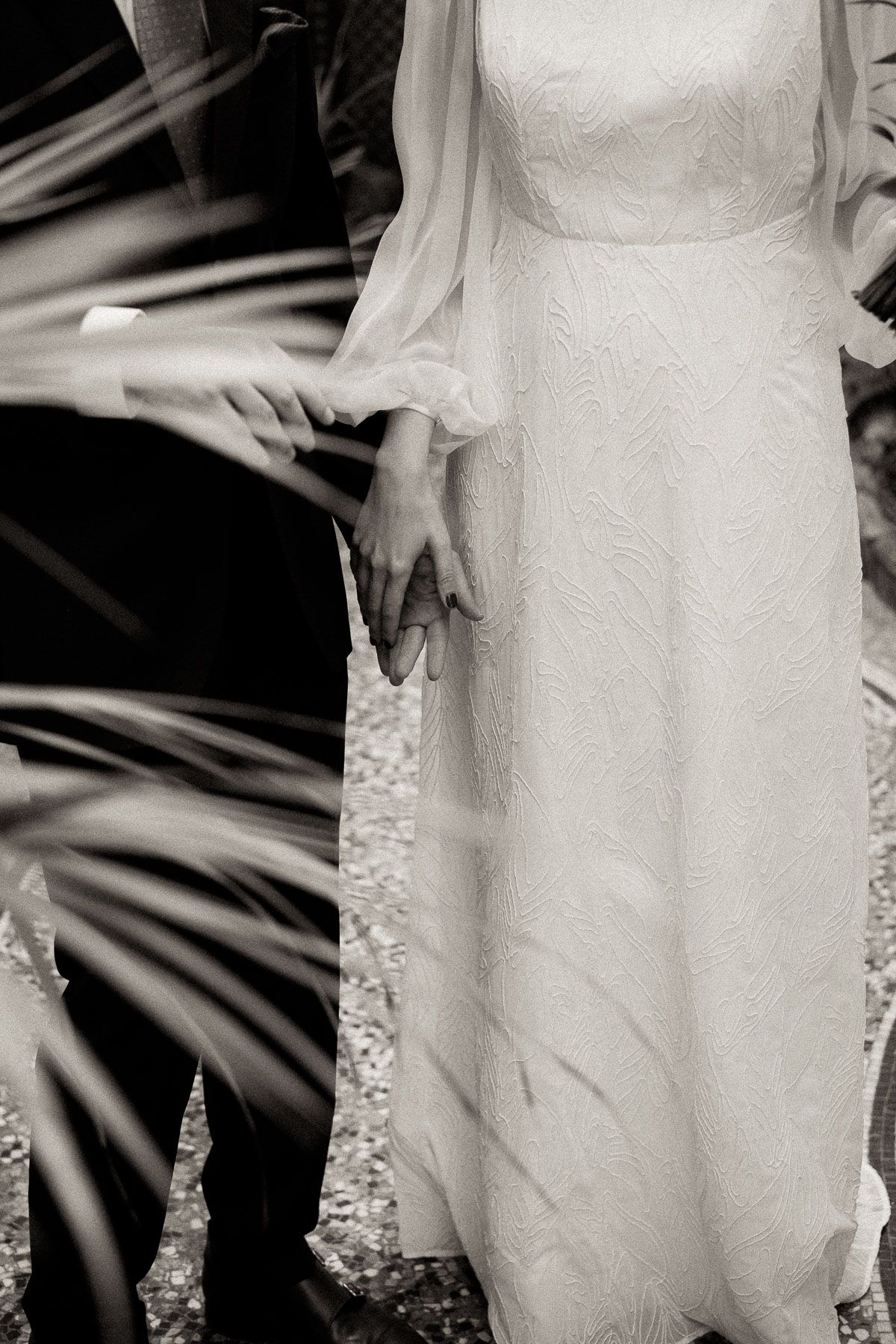 Close-up details of an elegant white lace wedding dress with intricate patterns.