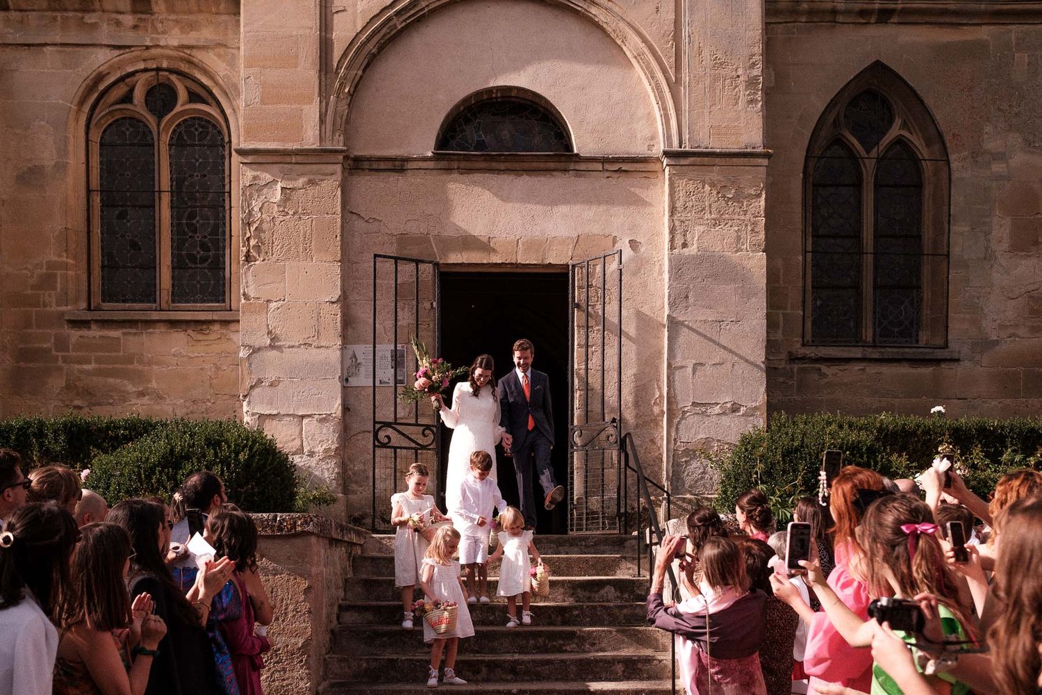 Wedding guests gather outside a historic stone church during a celebration ceremony.