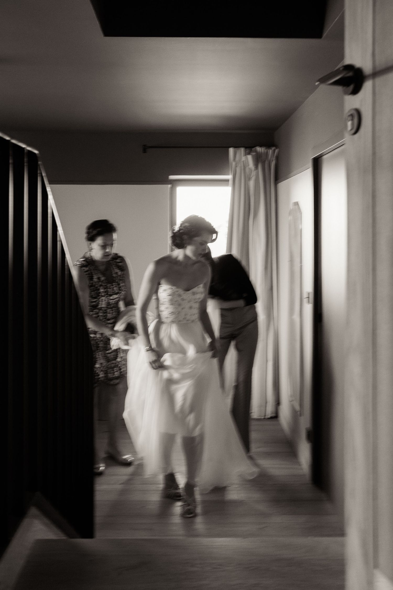 Blurred black and white motion sequence of people walking down a dimly lit hallway.