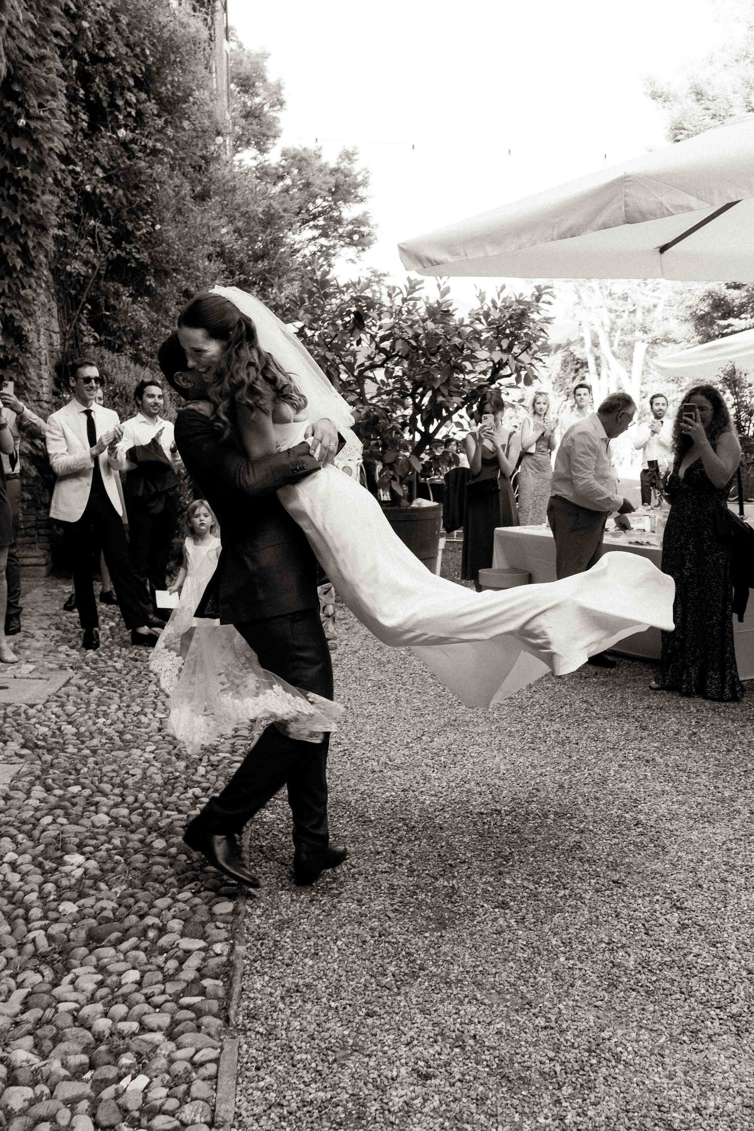 A sequence of black and white photos showing a wedding couple's veil blowing dramatically in the wind during an outdoor celebration.