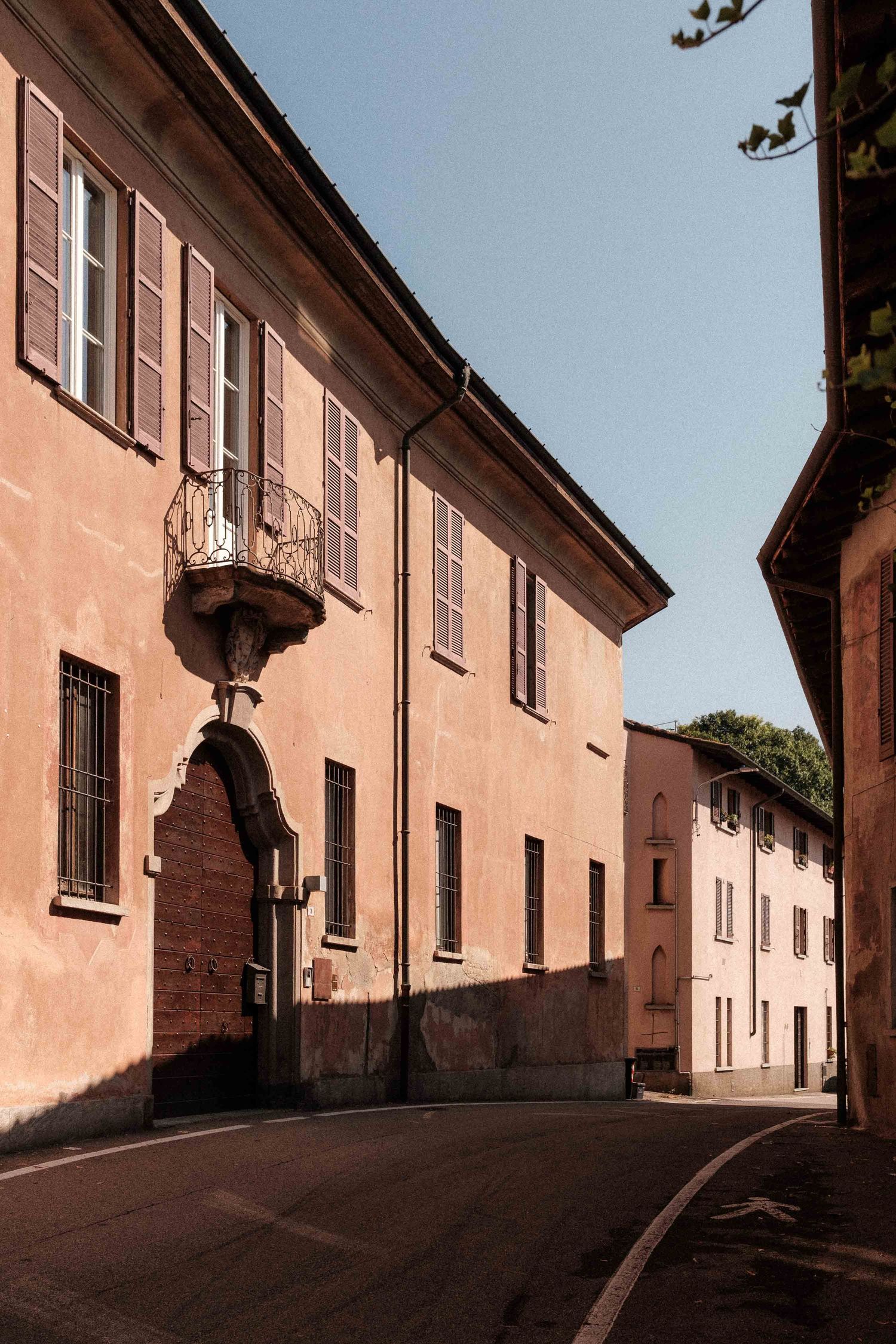 Upward view of a narrow cobblestone street lined with pink-hued buildings and traditional architecture in an Italian town.