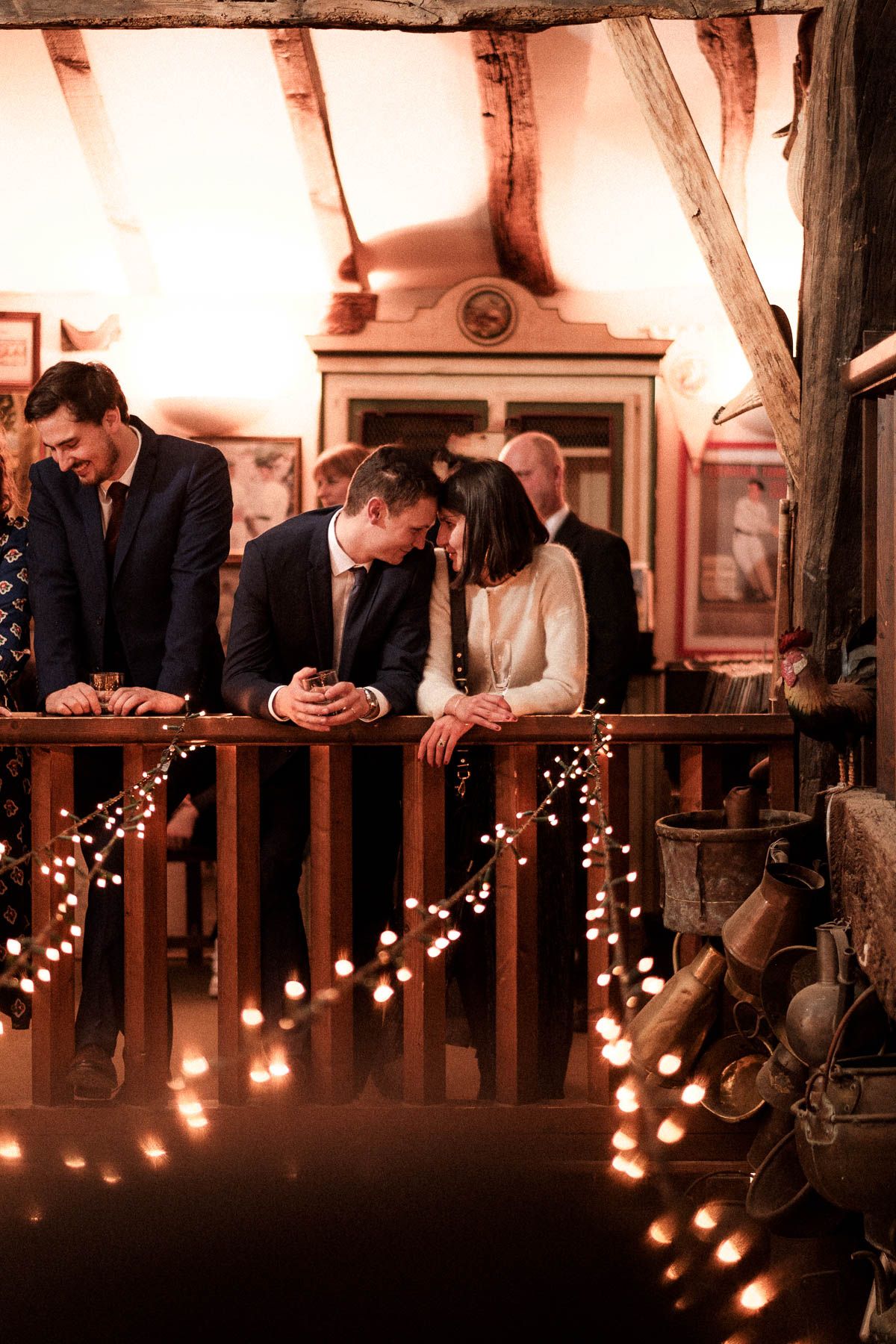 People gathered on a dimly lit balcony with string lights creating a warm, romantic ambiance.