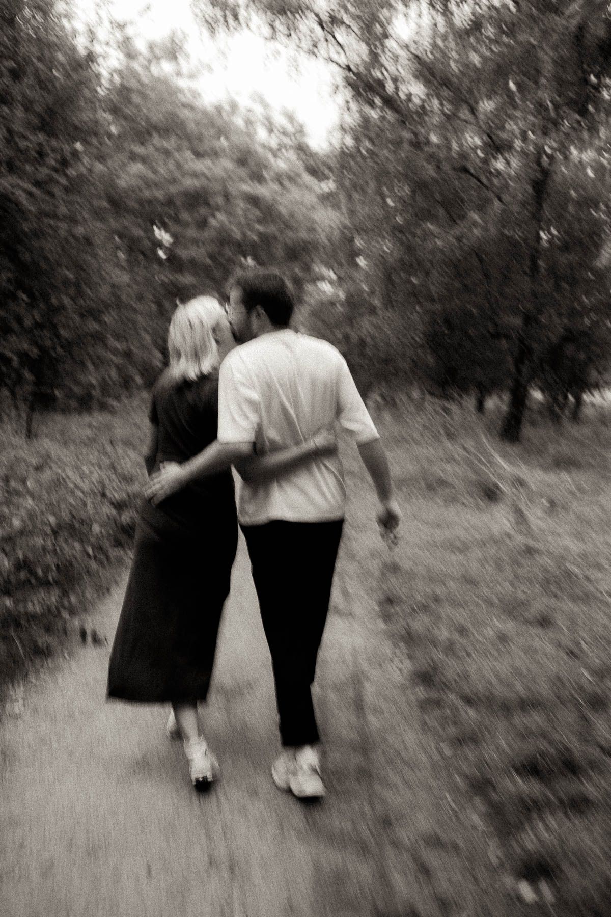 A black and white photo series shows a couple walking together down a wooded path, gradually fading into the distance.