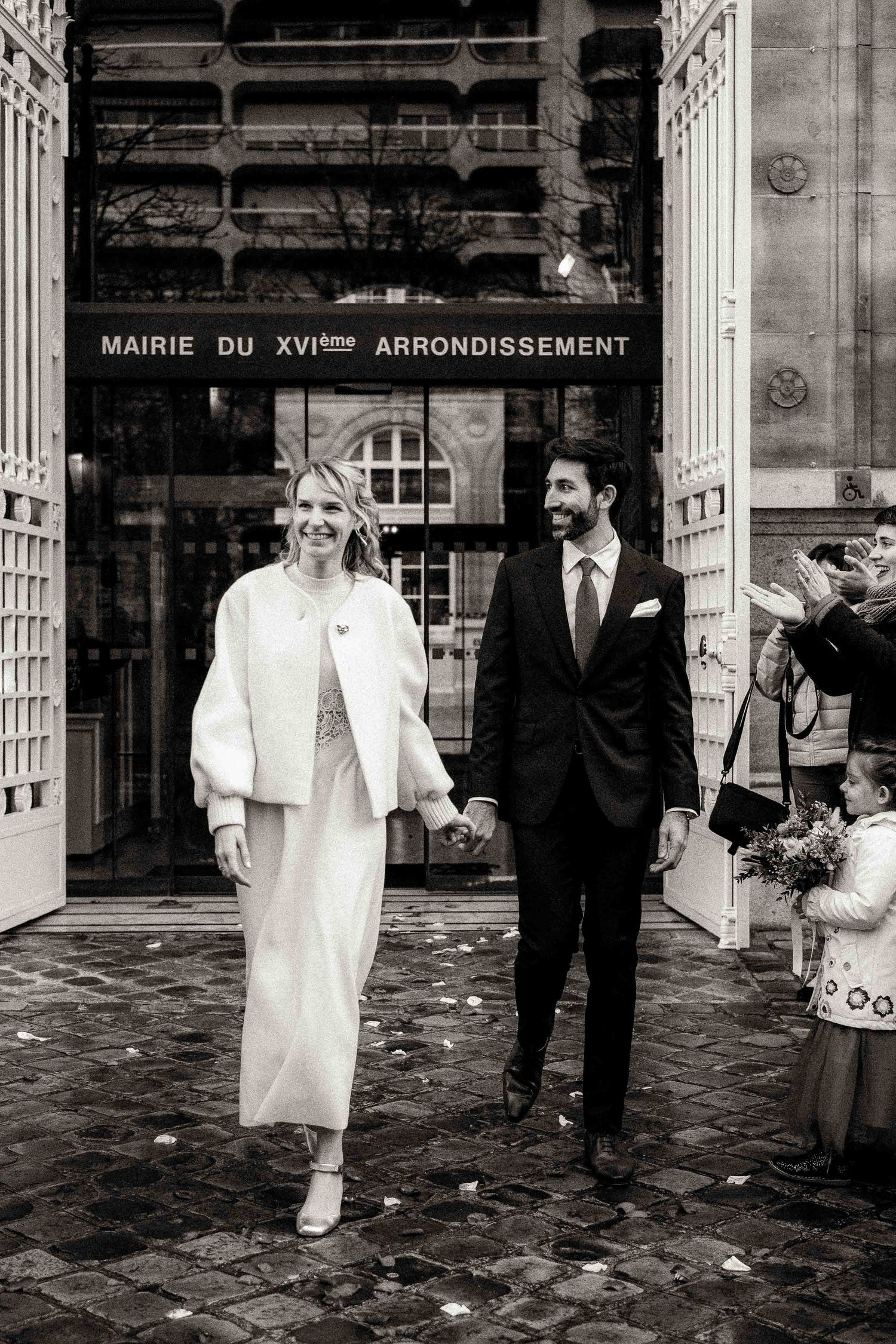 A series of five black and white wedding photographs showing a couple exiting a city hall building in Paris.