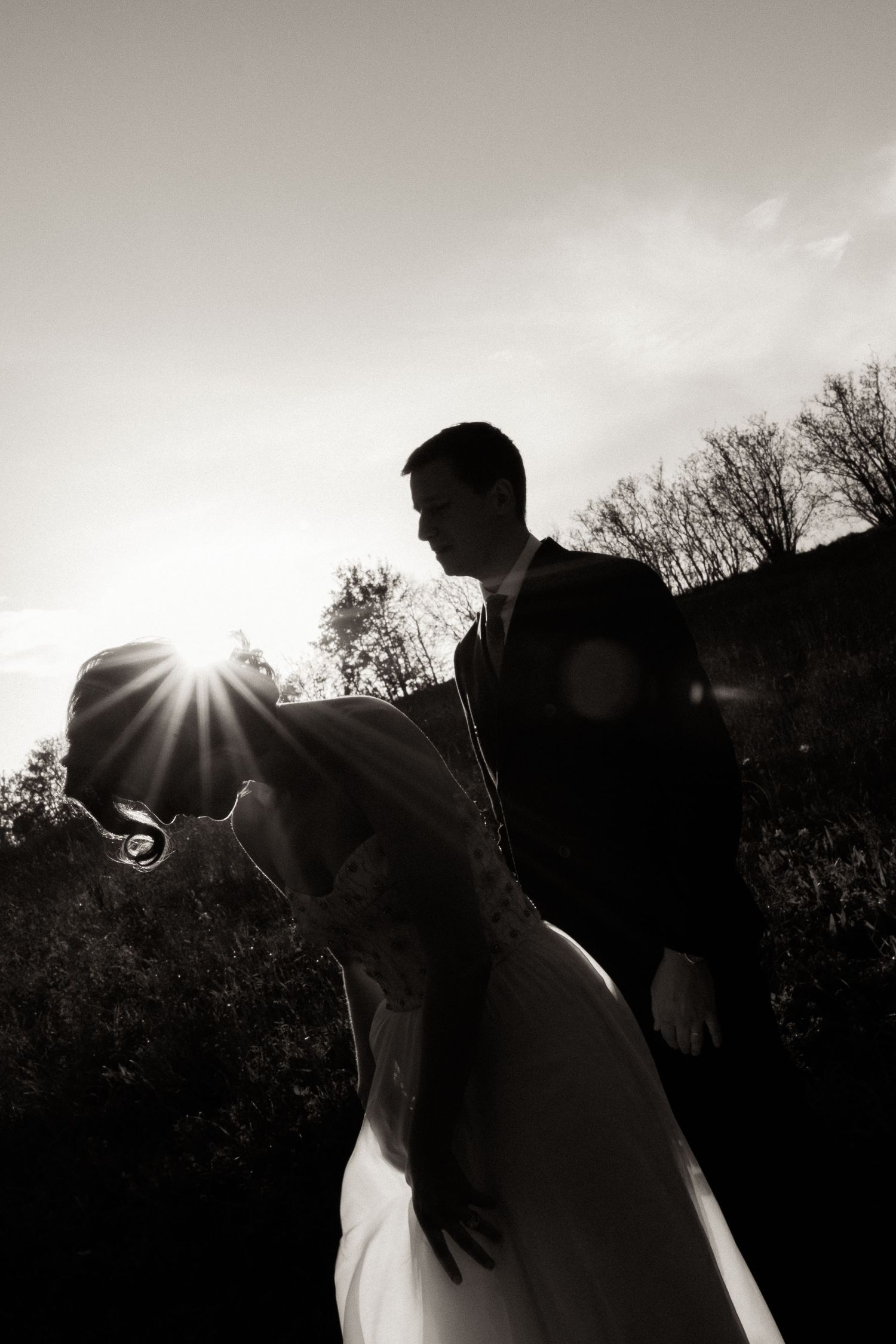 A series of silhouetted figures against a bright backlit sky with sun flare creating a dramatic contrast effect.
