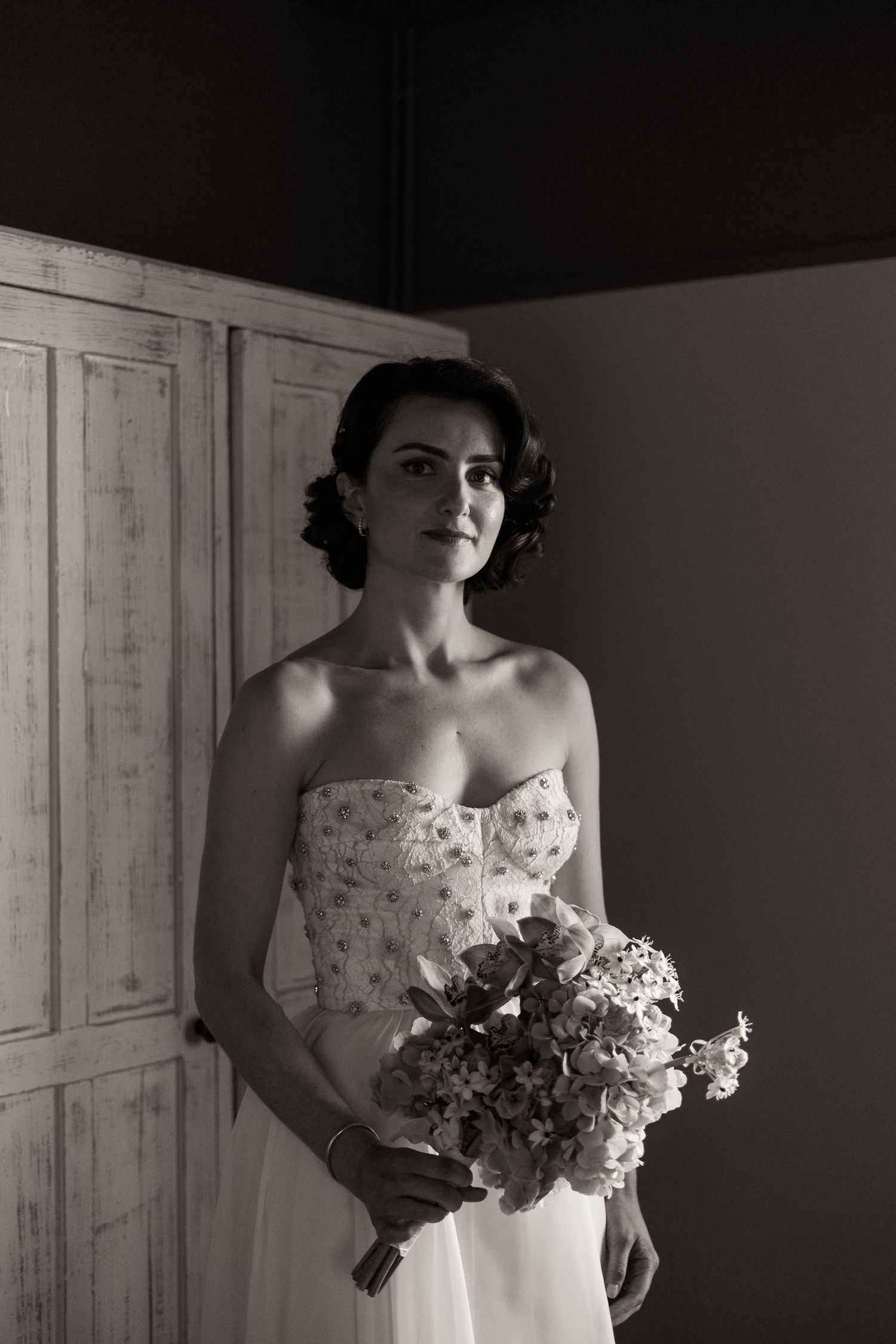 Black and white portrait series showing a bride in a sleeveless gown holding a floral bouquet.