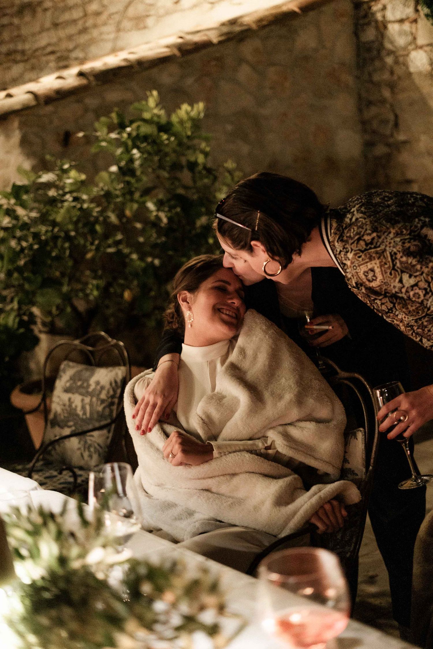 A romantic sequence of intimate moments captured between a couple in warm lighting against a rustic stone wall backdrop.
