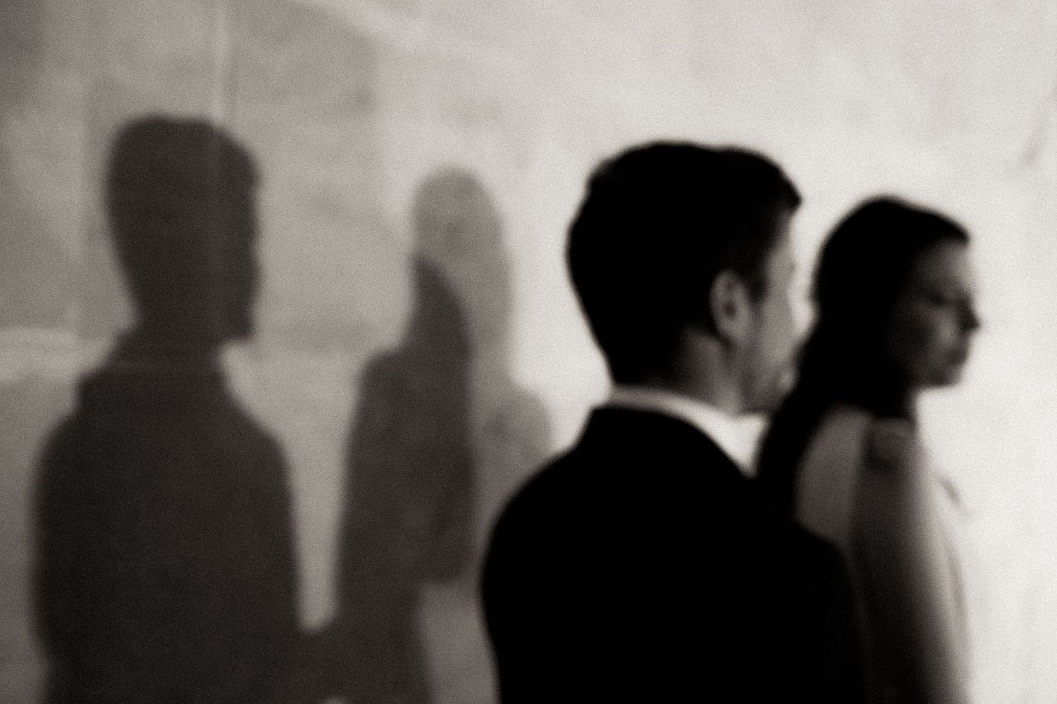 A series of black and white silhouettes of people standing in a line against a light background.