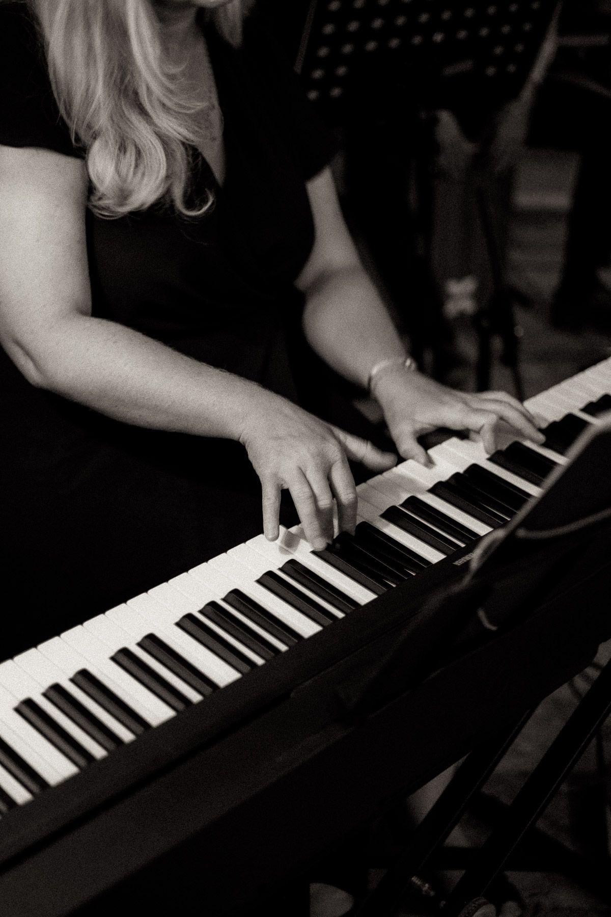 A series of black and white photos showing hands playing piano keys in dramatic lighting.