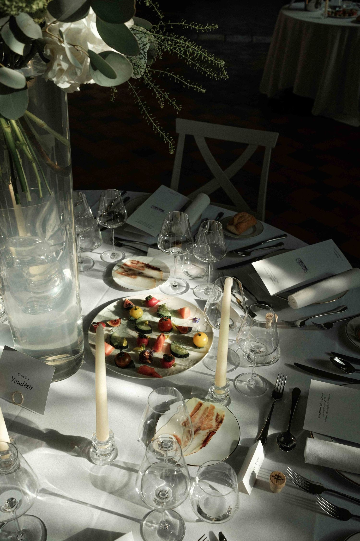 An elegant table setting at a fine dining restaurant with white linens, wine glasses, and plated dishes in natural light.