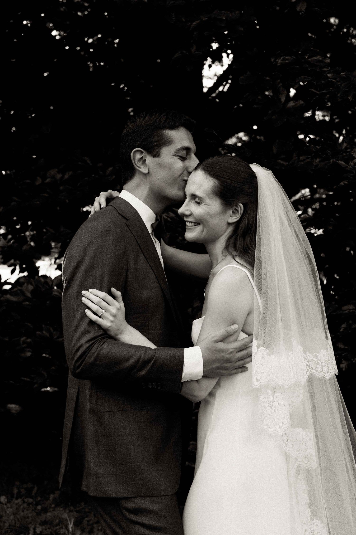 A couple shares an intimate dance moment at their wedding with the bride wearing a flowing white veil.