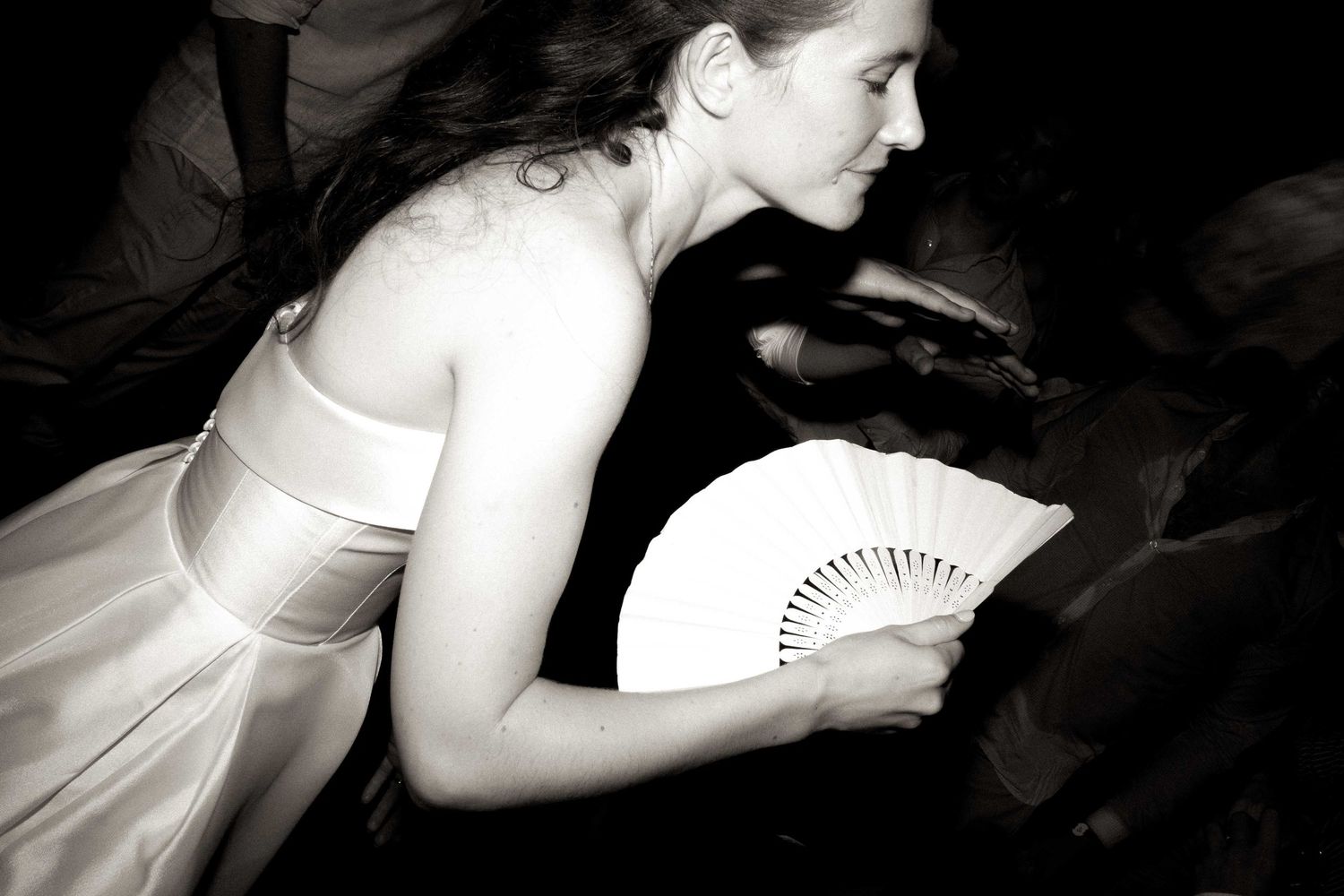 A series of black and white photos showing a bride in a wedding dress holding a fan in various artistic poses.