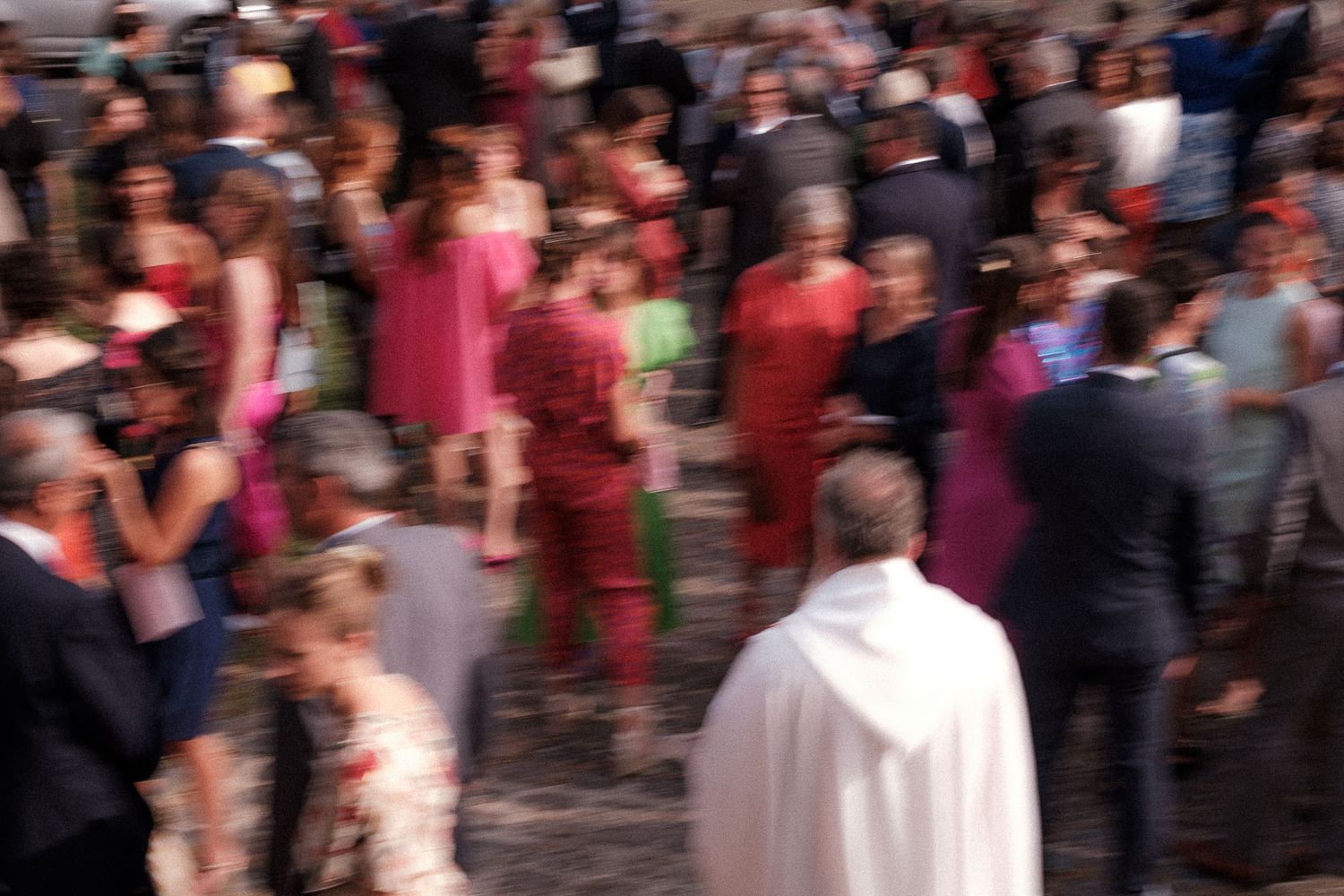 A blurry crowd of people dancing and celebrating at what appears to be a festive outdoor event or party.