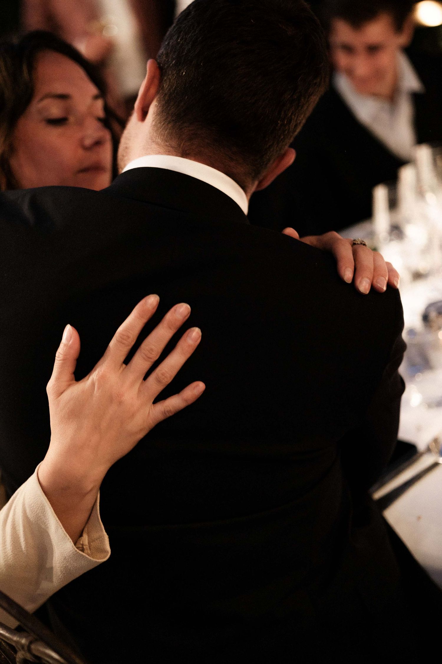 A series of intimate black and white photos showing hands embracing during what appears to be a formal event.