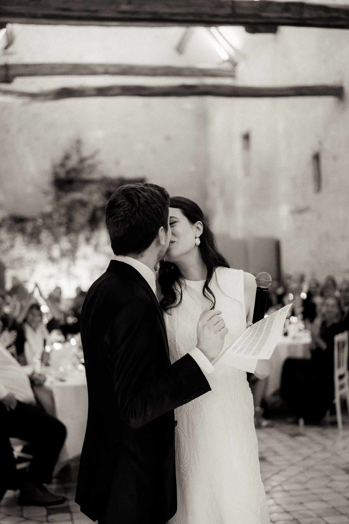 A romantic black and white photo of a couple sharing an intimate moment during their wedding reception.