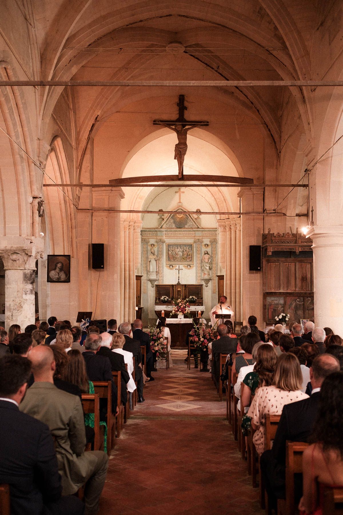 A panoramic view of people gathered inside a historic church with vaulted ceilings and arched corridors.