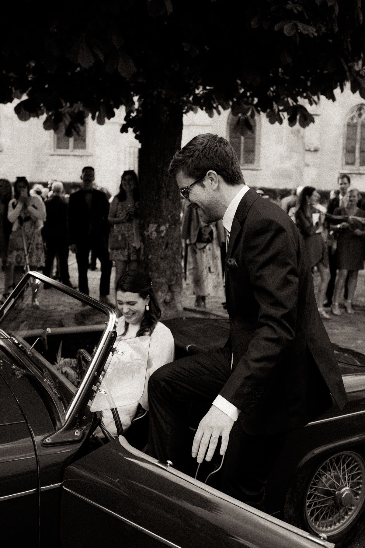 A black and white wedding photo sequence showing a couple entering a classic vintage car after their ceremony.