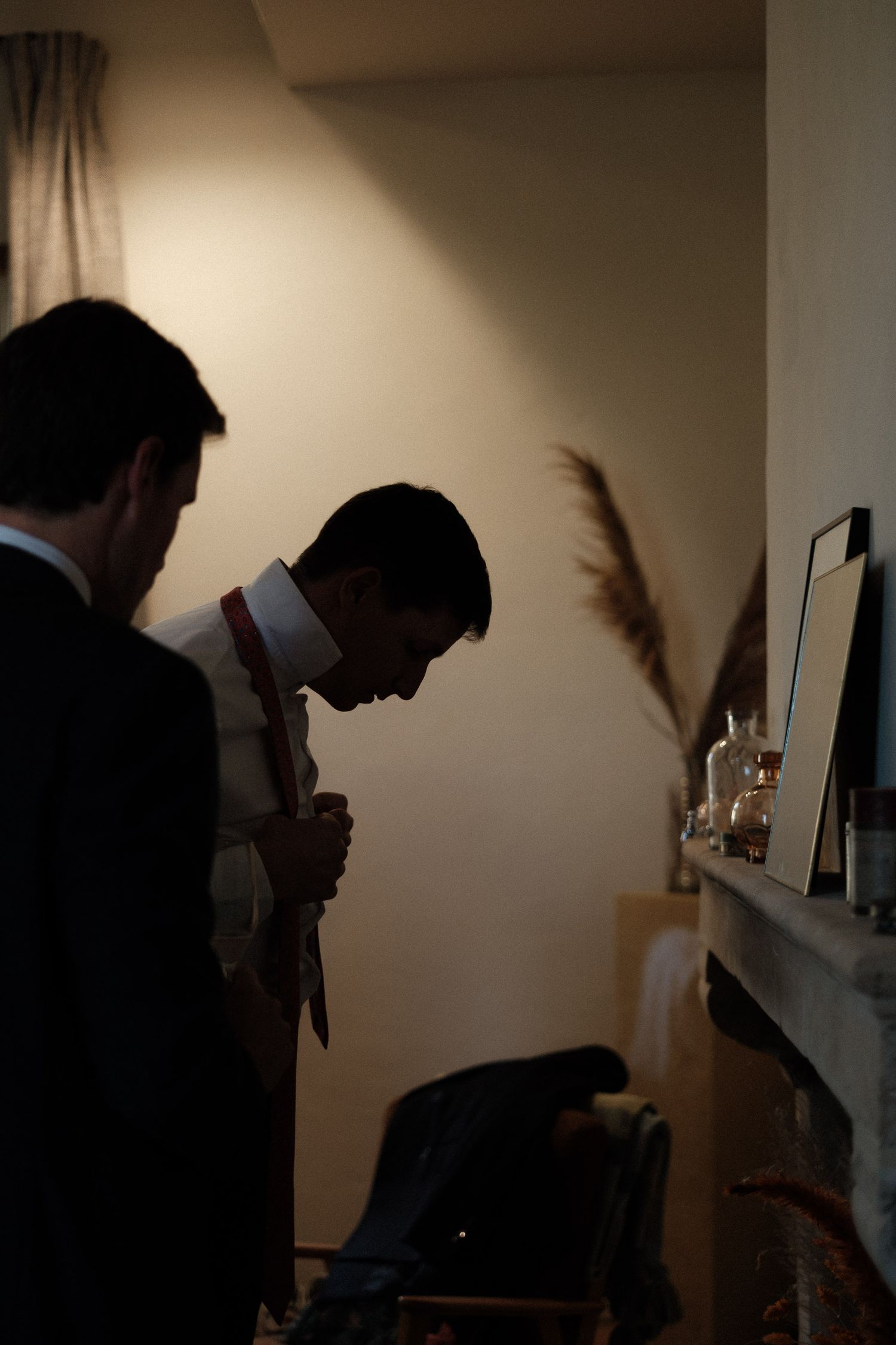 Silhouettes of figures looking at items displayed on wall-mounted shelves in moody lighting.
