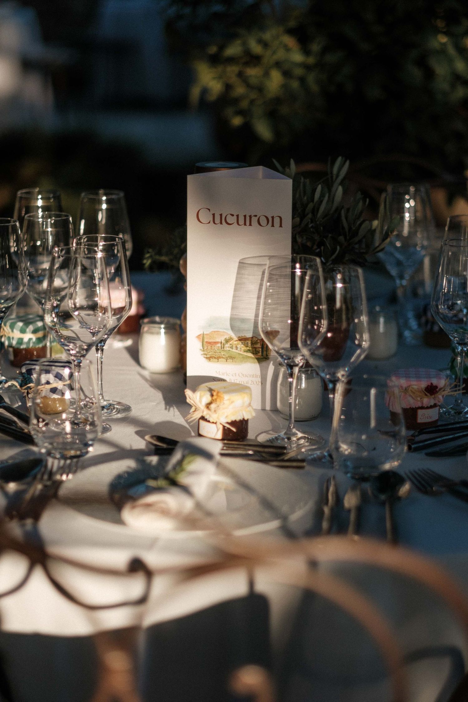 Wine glasses and place settings arranged on an elegant dining table with soft lighting and shadows.