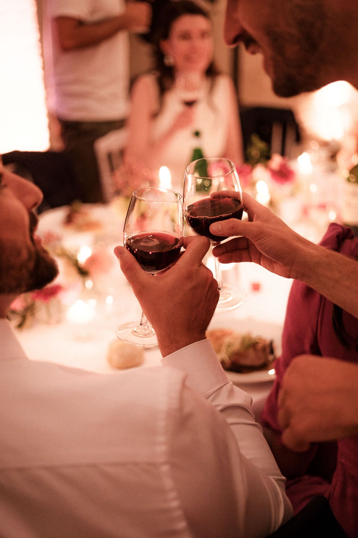 Hands holding chocolate dessert cups in a dimly lit restaurant setting with warm candlelight ambiance.