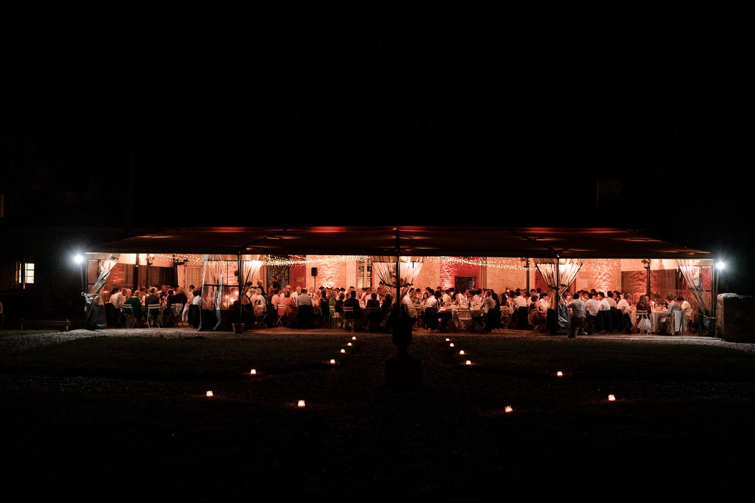 Long exposure panoramic nighttime shot of an illuminated outdoor wedding reception venue.