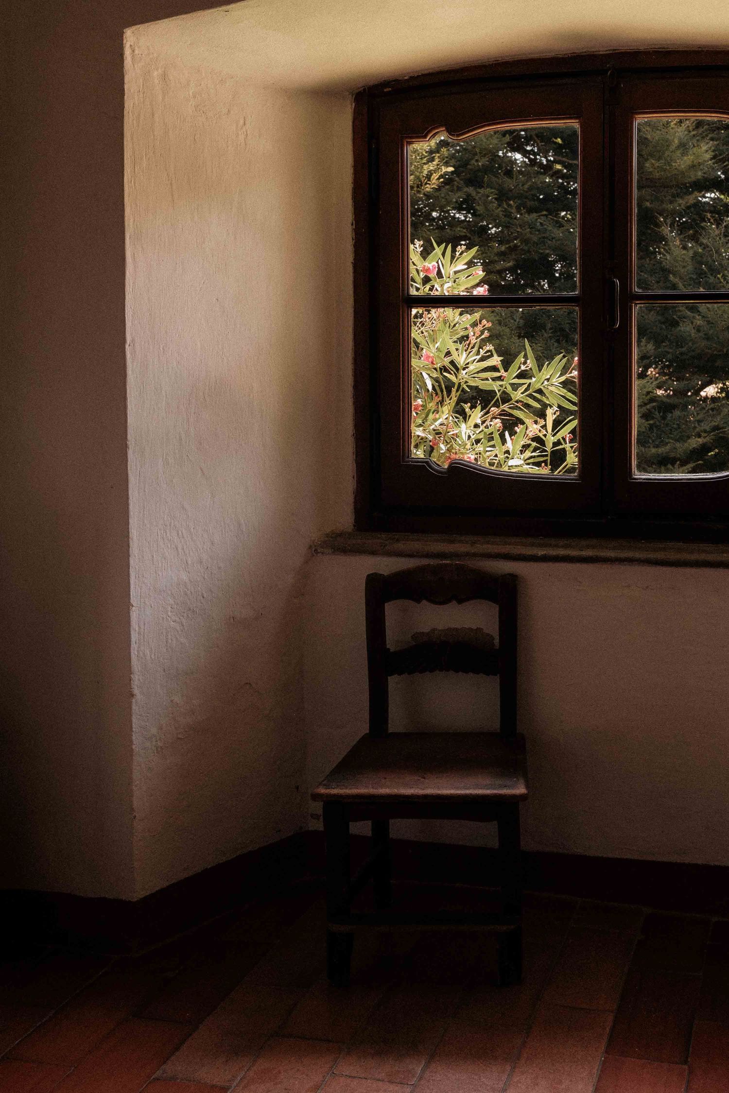 Four dark moody interior photos showing an empty room with wooden floors, white walls, and a solitary chair by the window.
