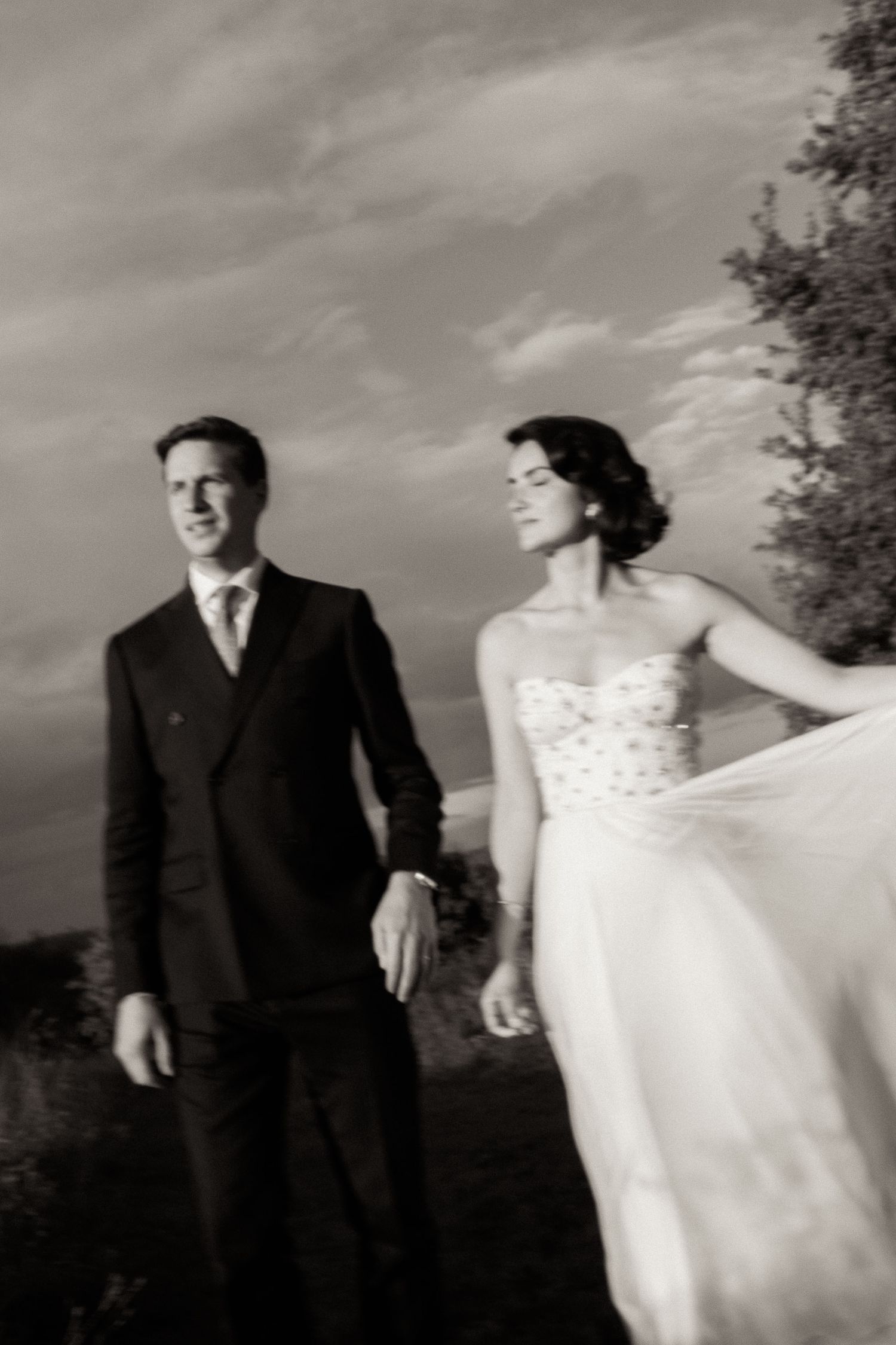 Black and white wedding photo sequence showing couple walking and dancing together in formal attire outdoors.