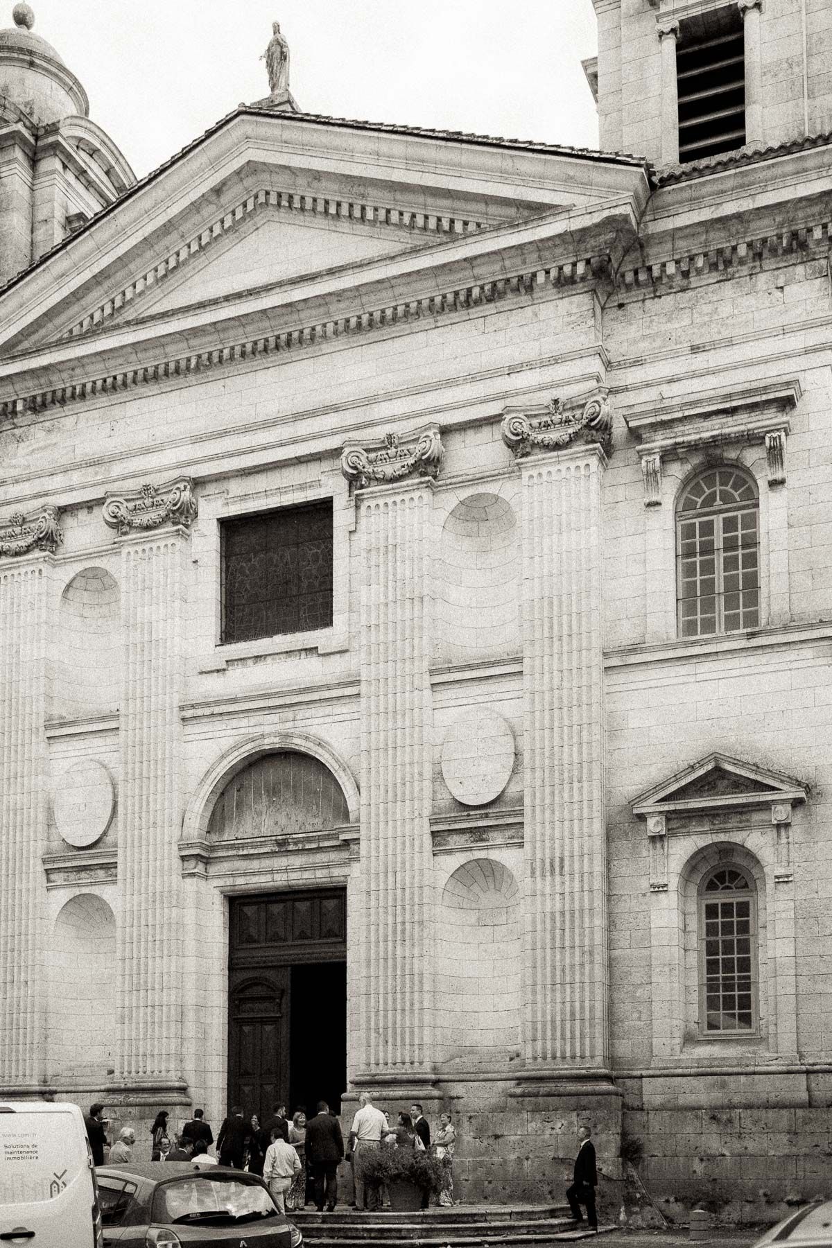 Historic white stone cathedral facade with classical columns and arched windows shows architectural details in black and white.
