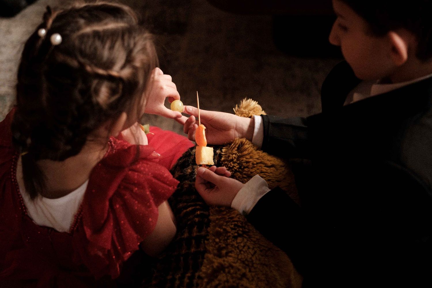 A person eating a crispy chicken wing at a dimly lit restaurant.
