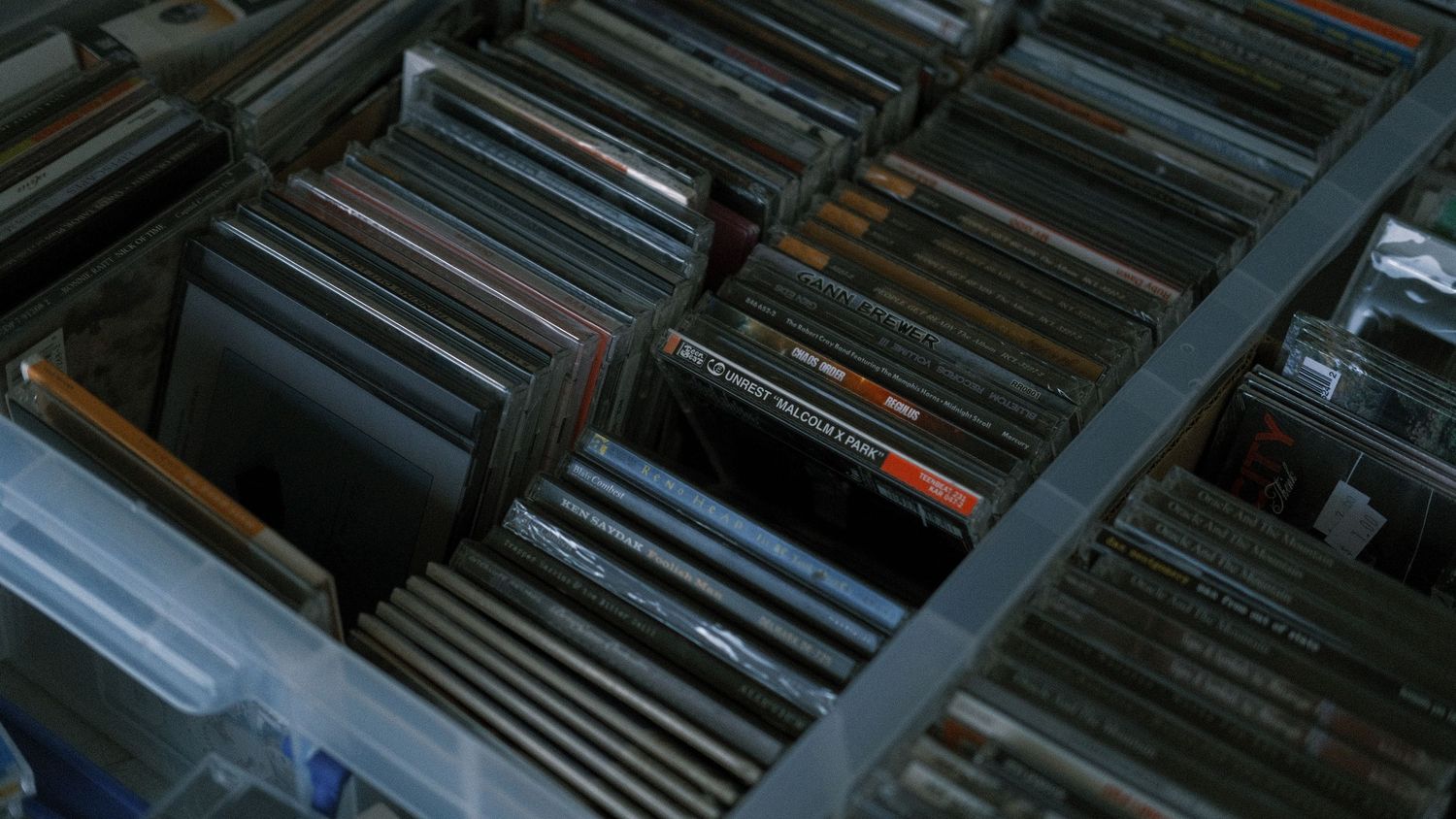 Large collection of CDs organized in plastic storage bins, showcasing a diverse music library.
