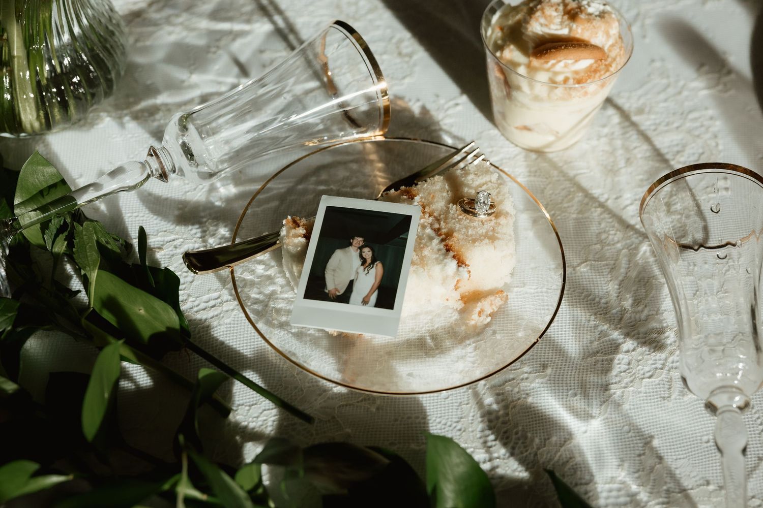 Polaroid photo of newlyweds displayed on a glass plate with wedding cake at reception.