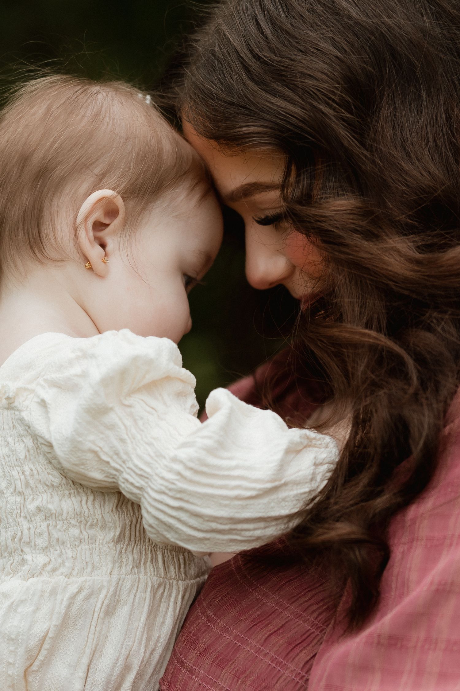 Close-up of mother and baby touching foreheads in tender moment.