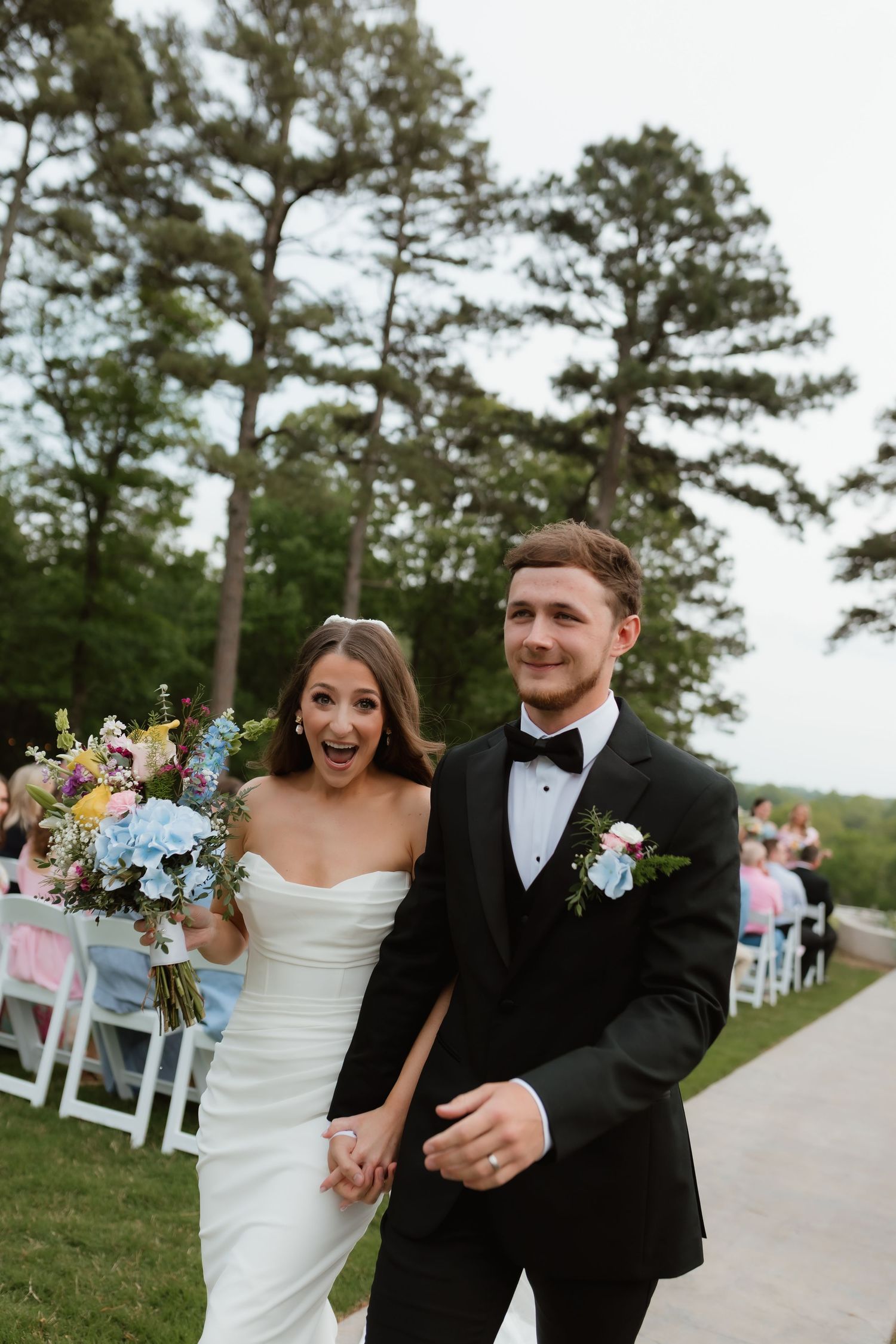 Joyful bride and groom walking down aisle after outdoor wedding ceremony.