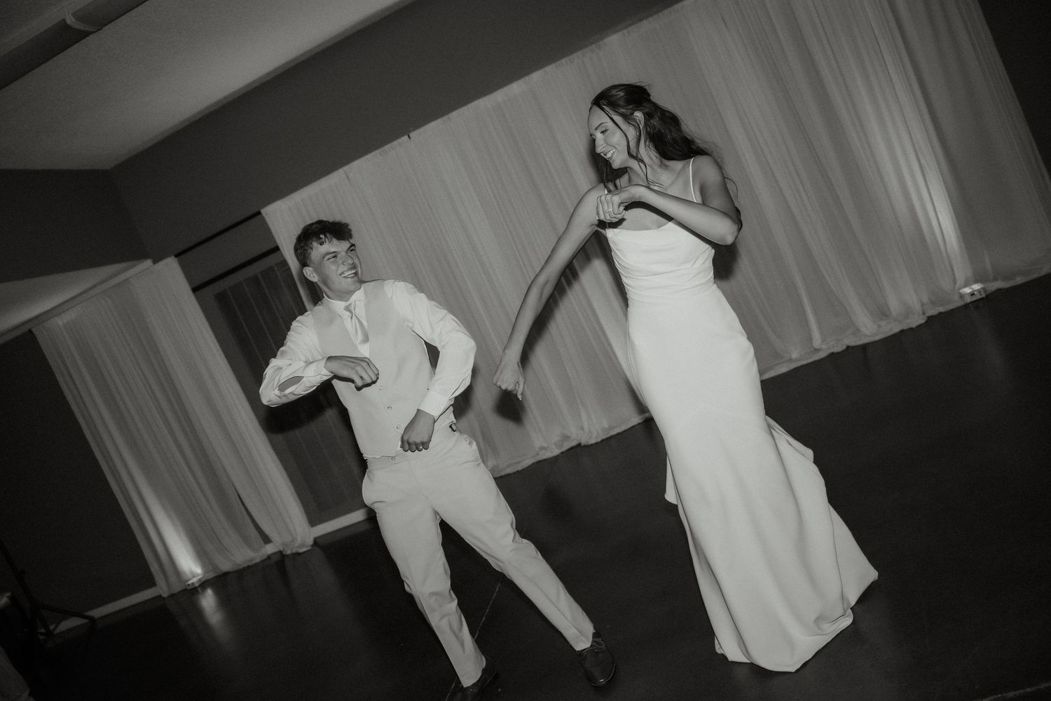 Bride and groom sharing fun first dance in black and white wedding reception photo.