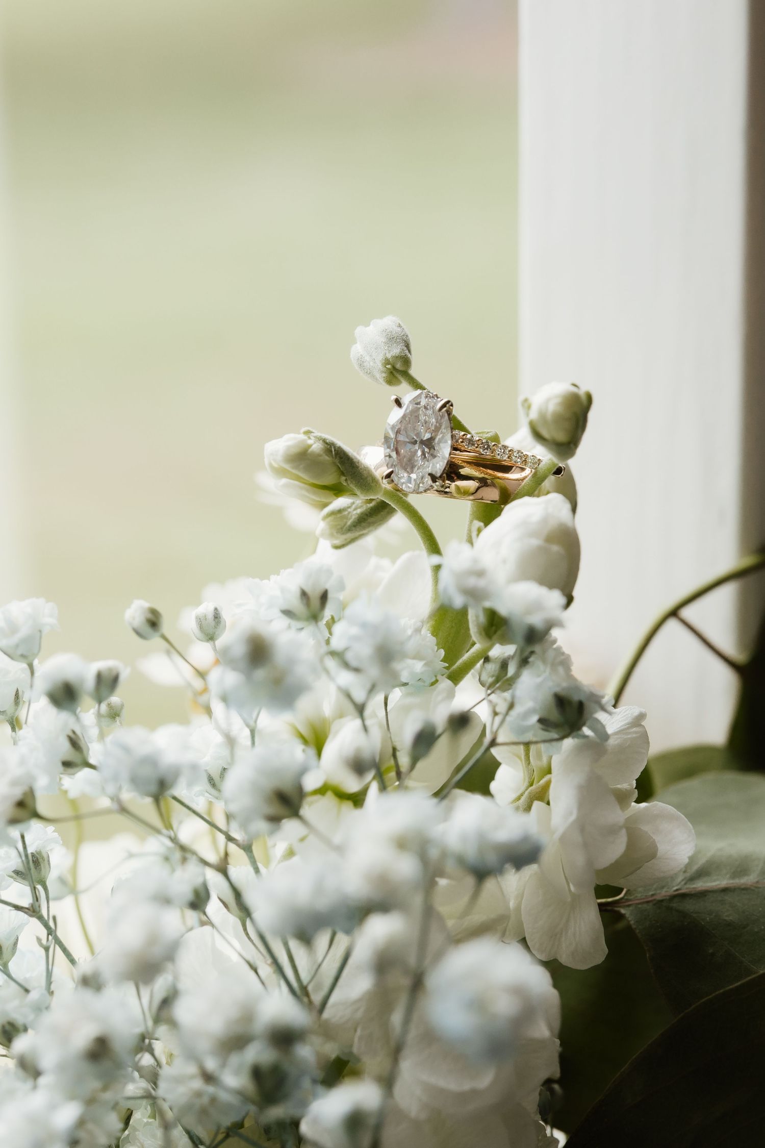 Diamond engagement ring nestled among white baby's breath flowers in a bridal bouquet.