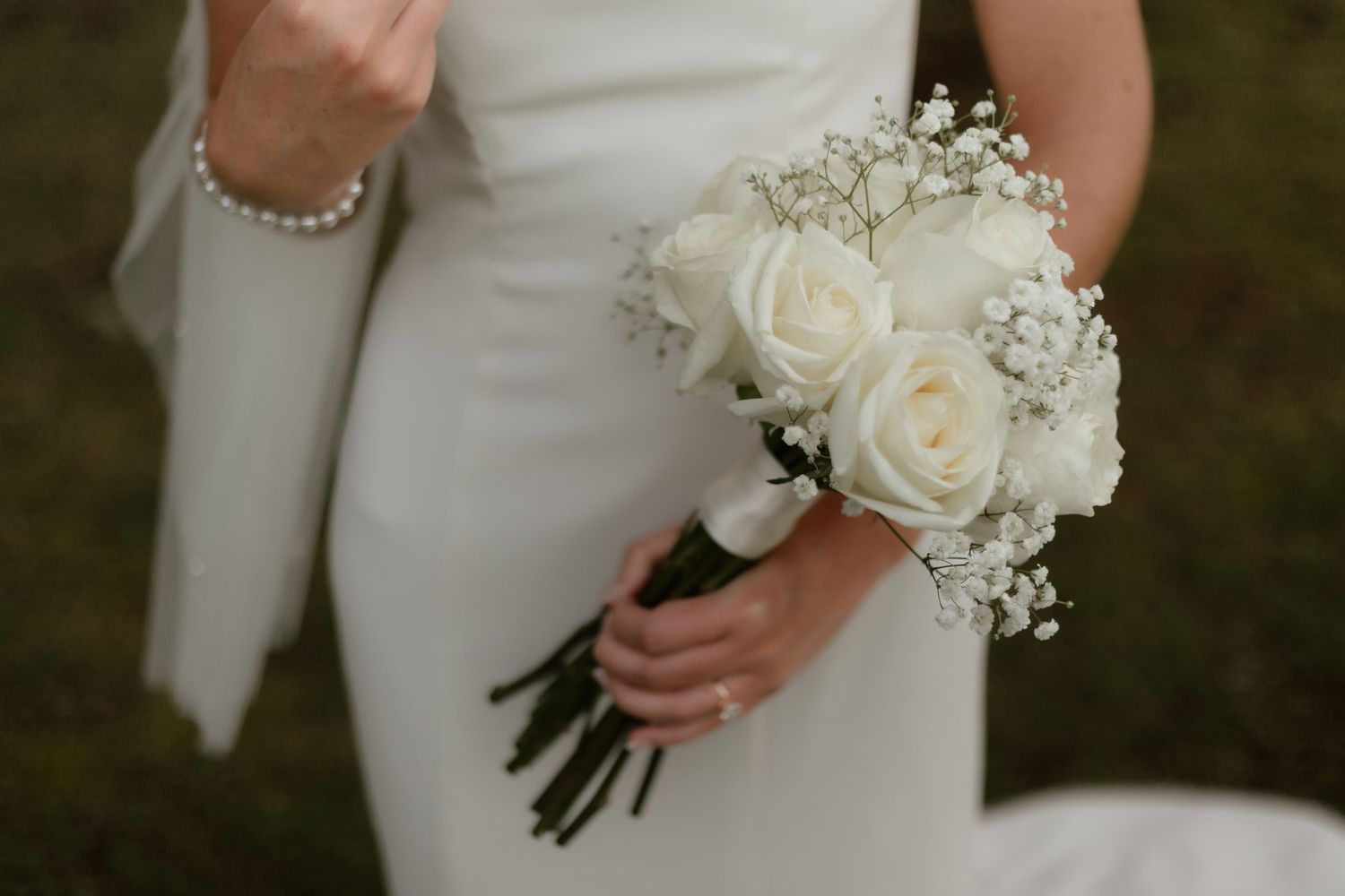 Bride holds a classic white rose and baby's breath bouquet on her wedding day.