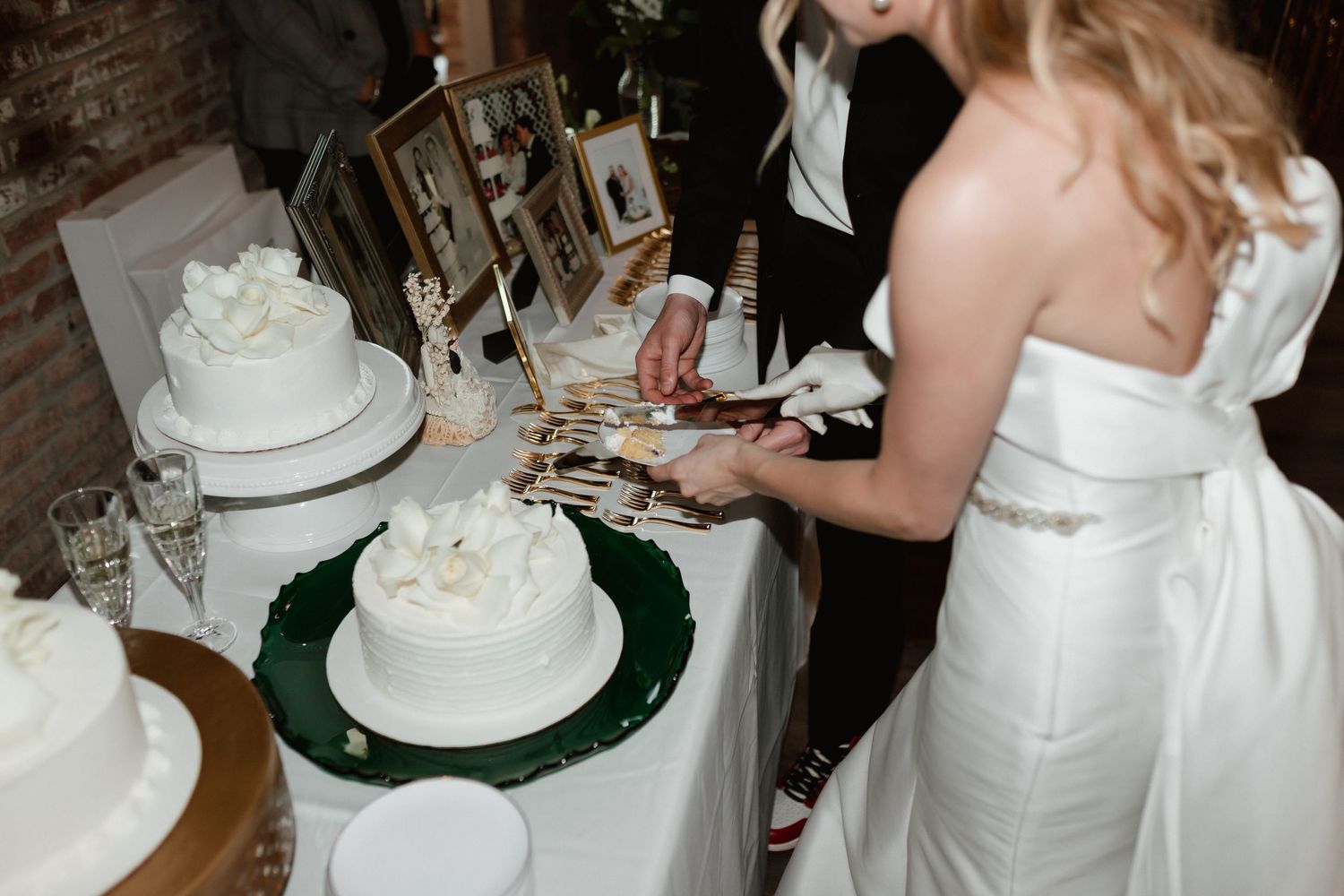 Bride and groom cut their white wedding cake together at reception table.