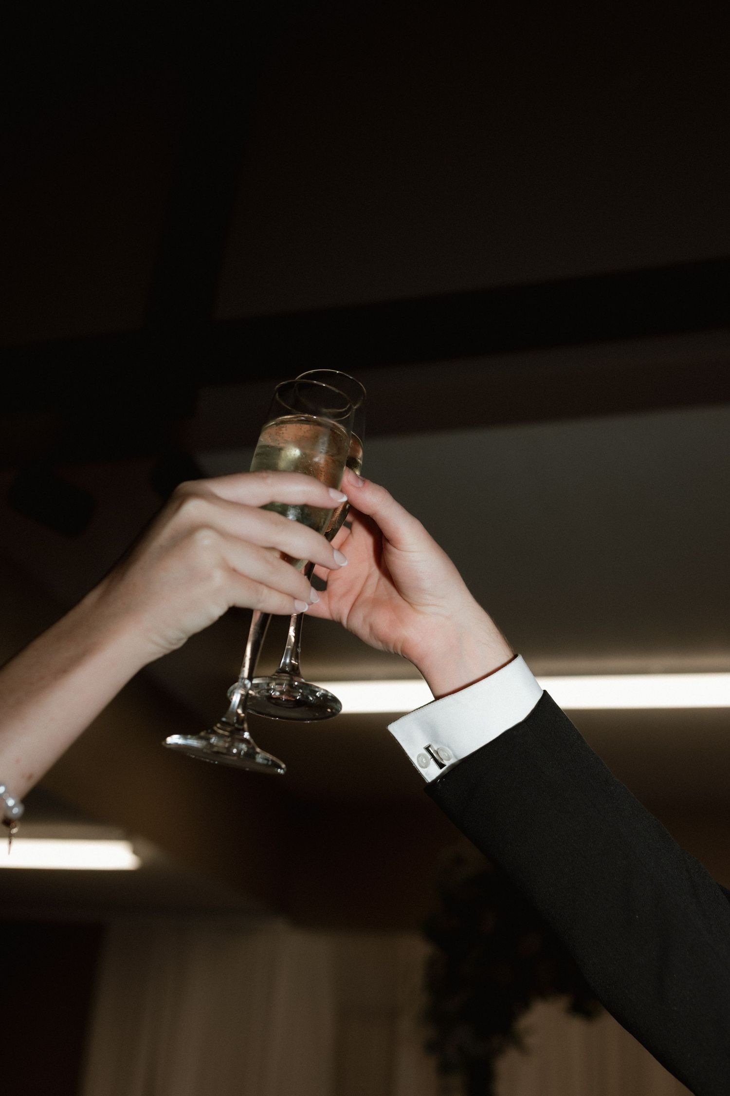 Bride and groom clink champagne flutes together in a celebratory toast at their wedding reception.
