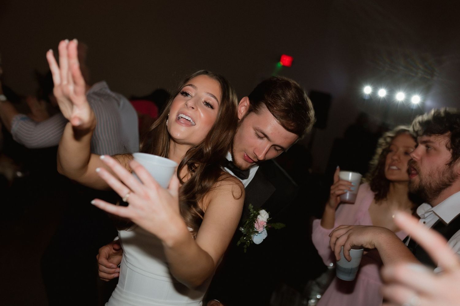 Bride and groom dancing together joyfully surrounded by guests at reception.