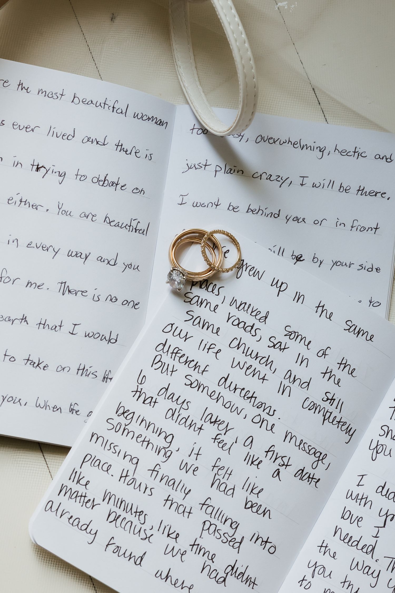 Gold wedding rings rest on handwritten vow letters, capturing an intimate wedding detail.