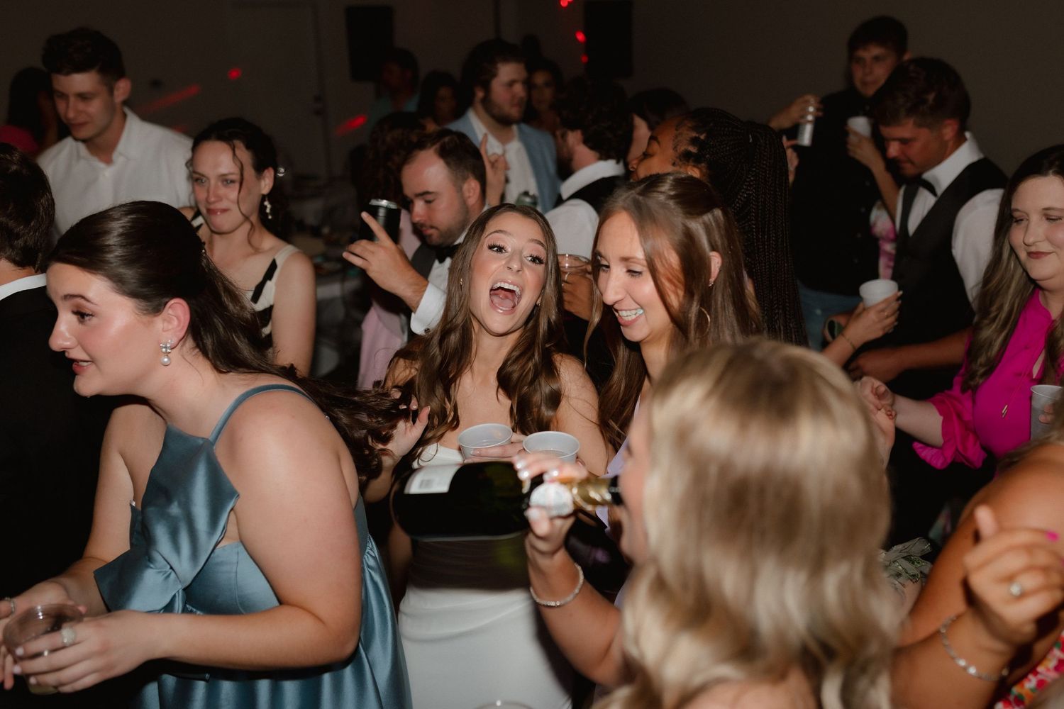 Wedding guests in formal attire dancing and celebrating at lively reception.