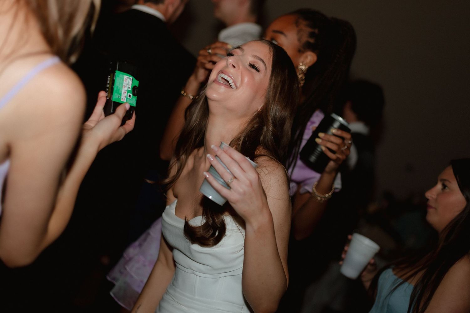 Bride laughing and dancing joyfully with guests at her wedding reception.