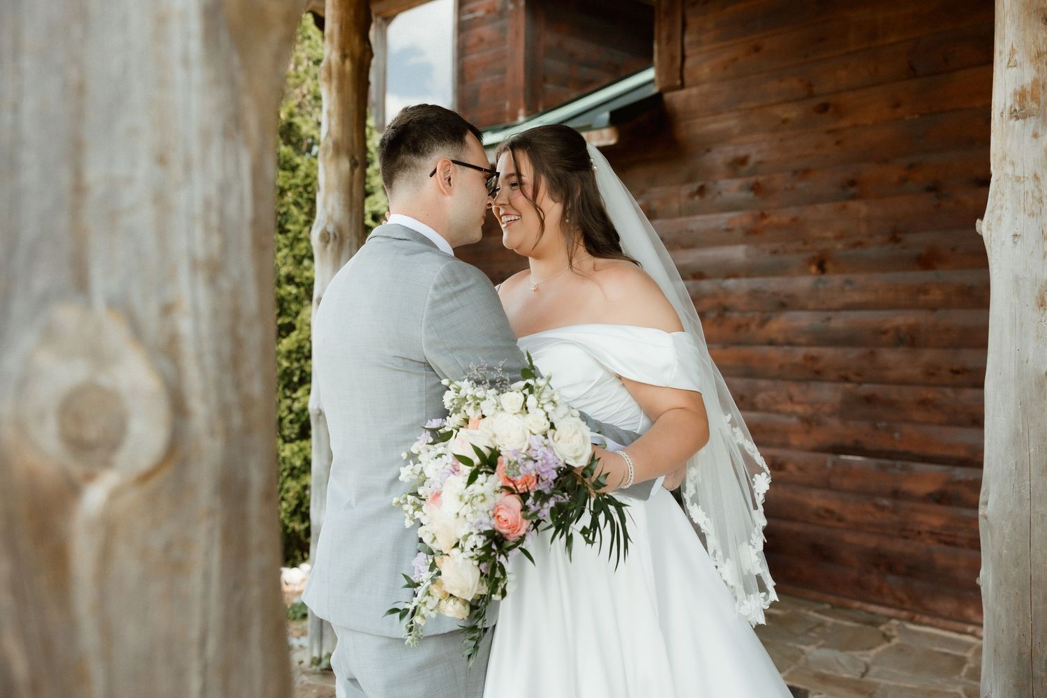 Bride and groom sharing romantic moment outside rustic wooden barn on wedding day.