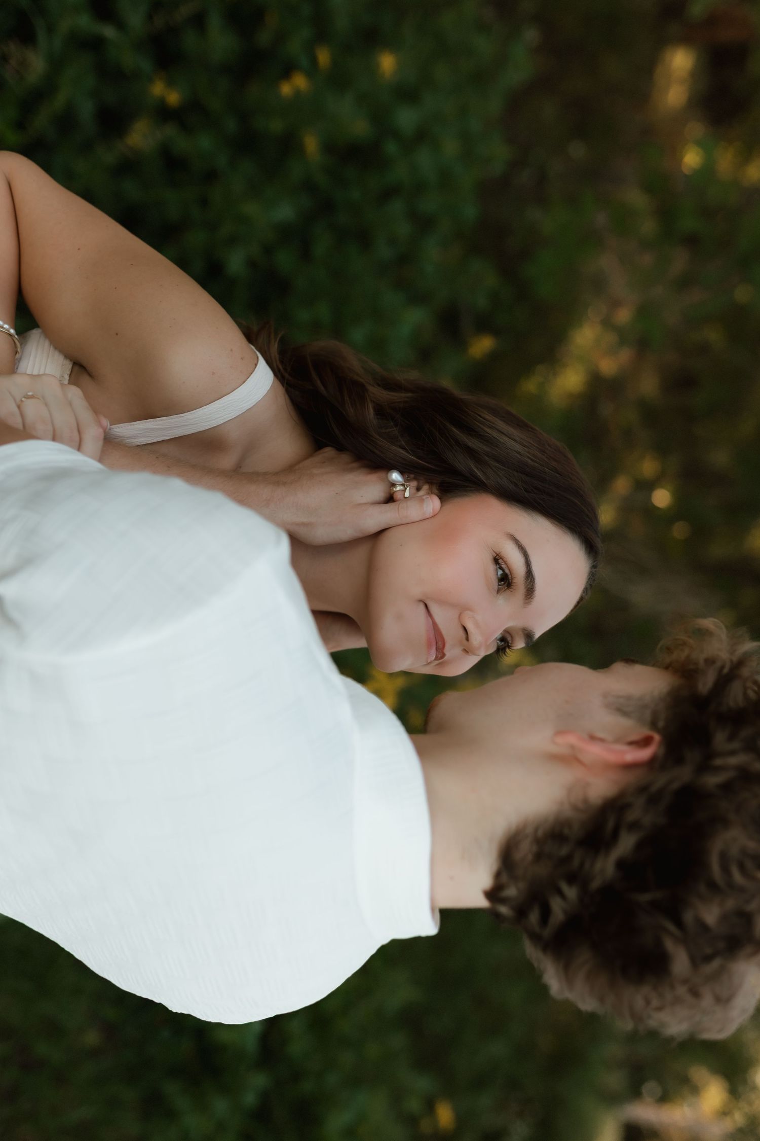 Romantic couple facing each other in lush garden, woman with pearl earring gazing at partner.