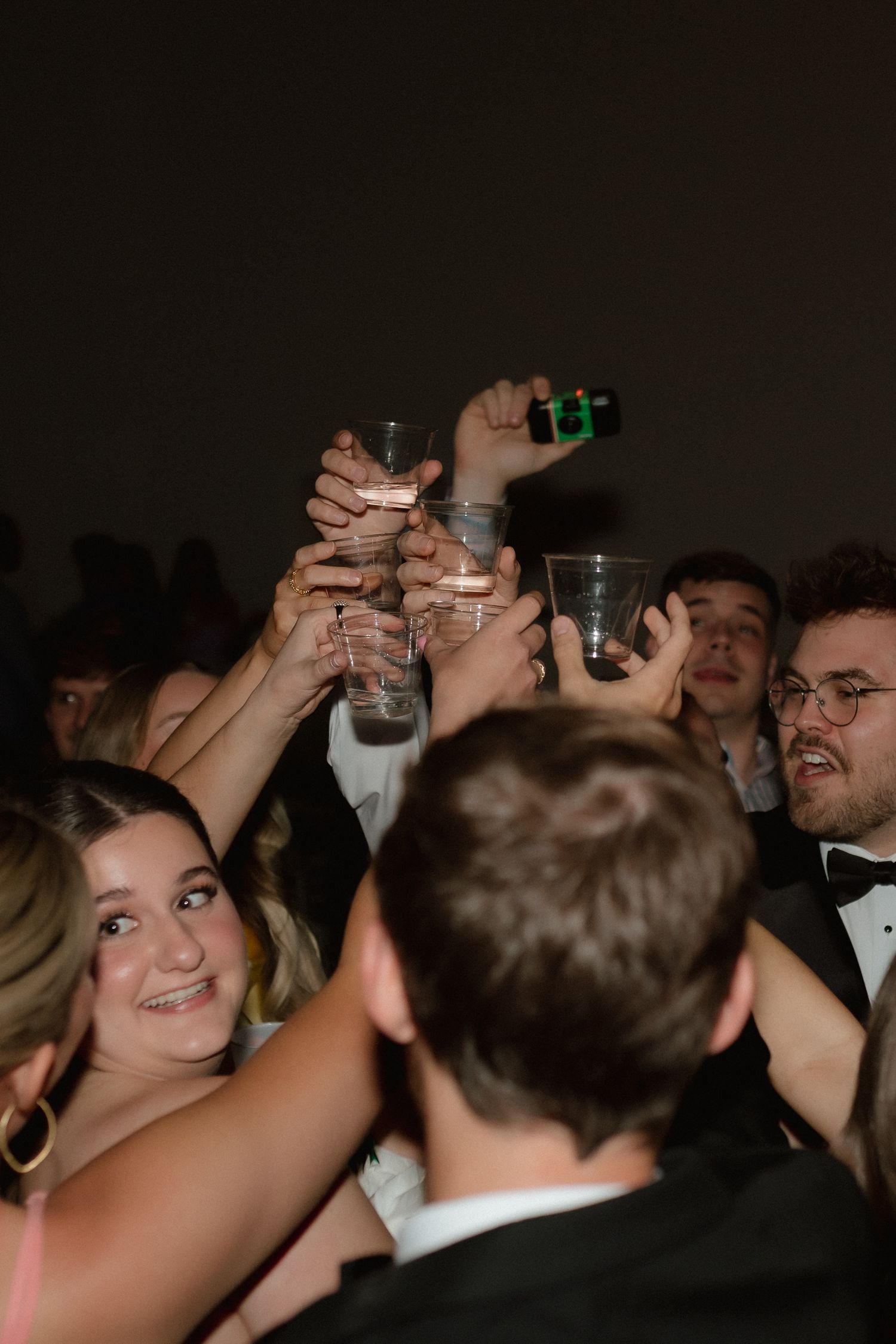 Wedding guests raise glasses in a celebratory toast on the dance floor at a reception.