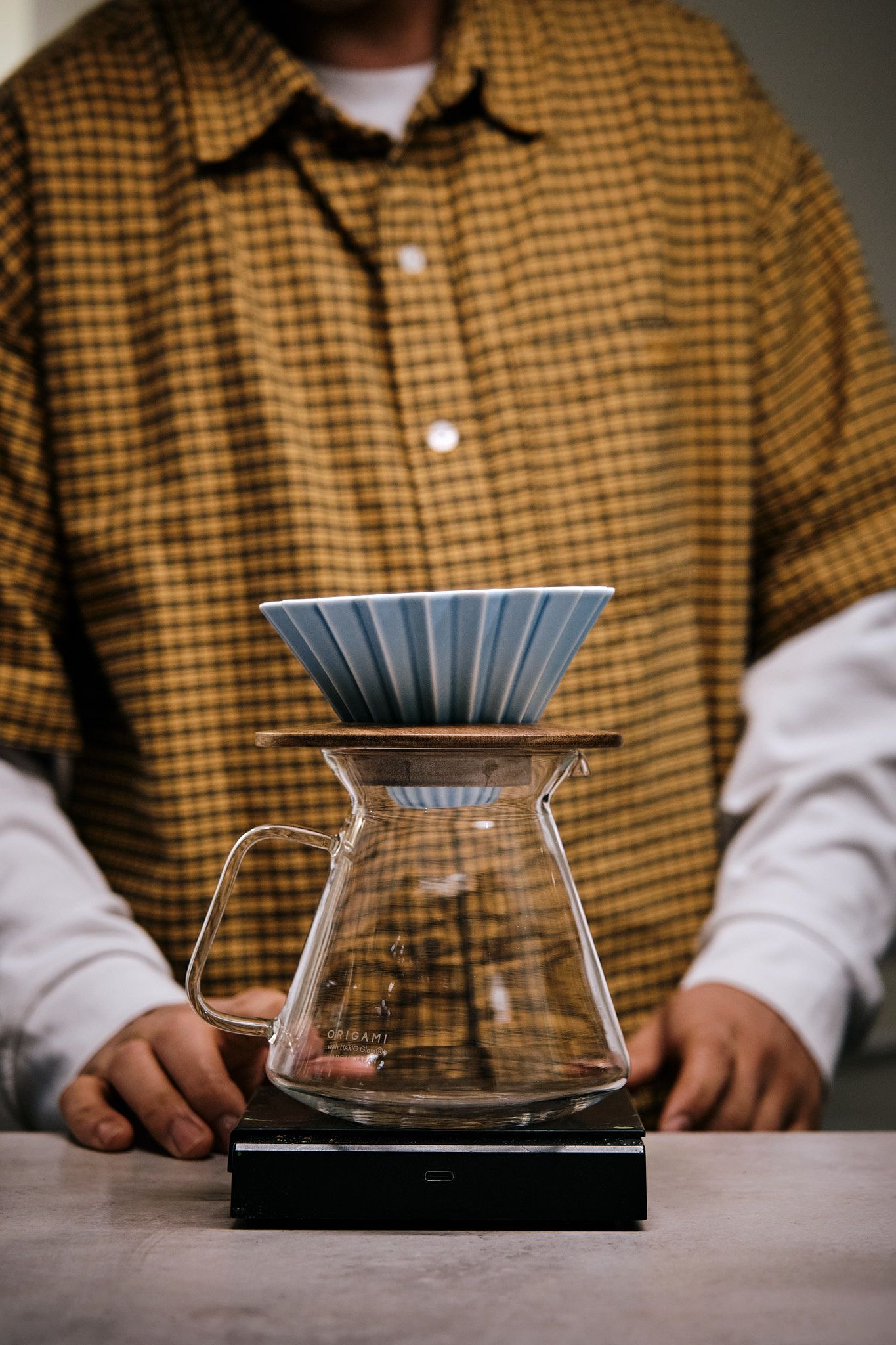 A Hario V60 coffee dripper setup with blue filter paper on a wooden surface.
