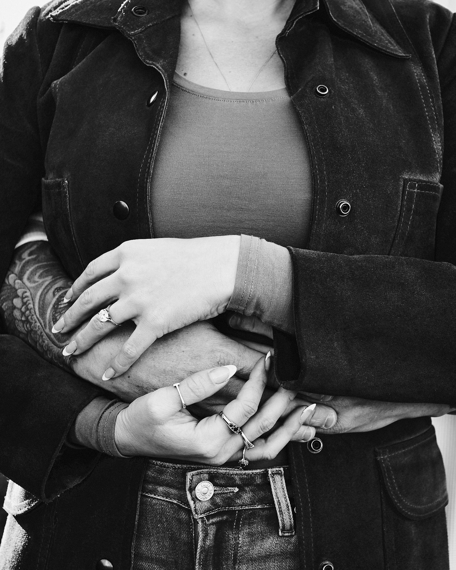 Black and white detail shot of hands and denim with rings and jewelry.
