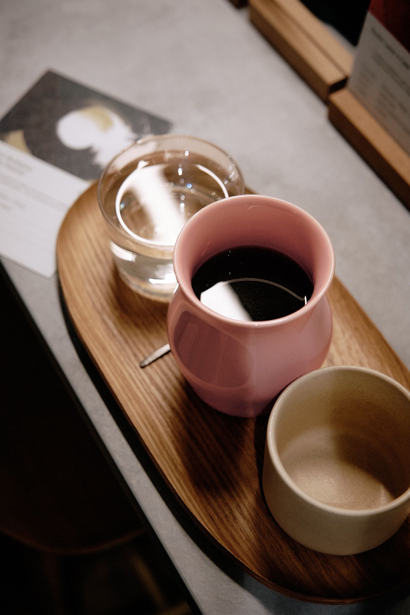 Coffee service on wooden tray with pink ceramic cup and water glass.