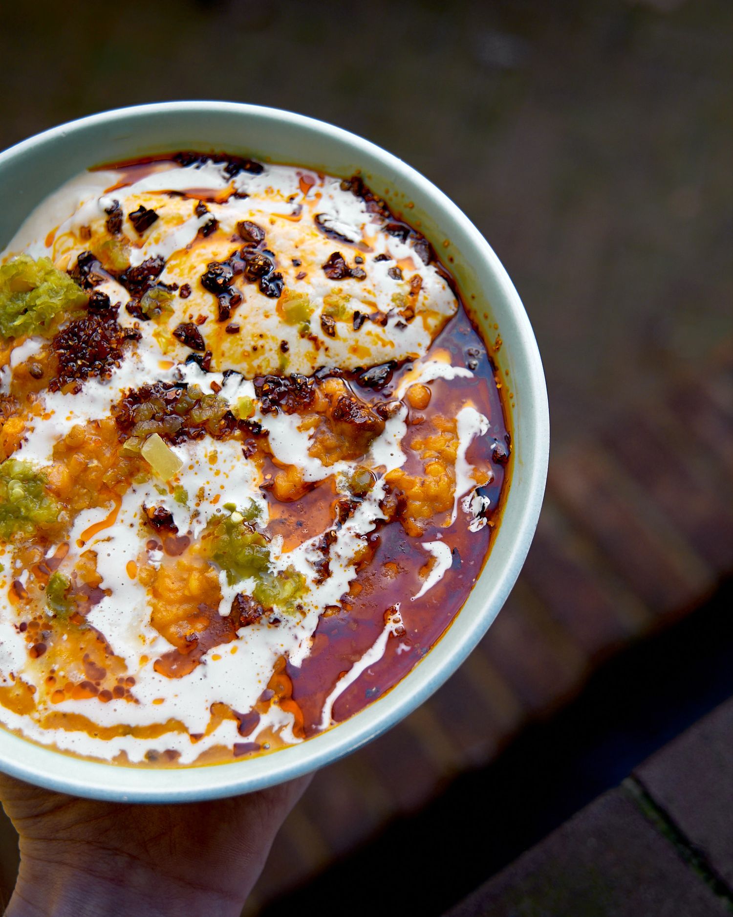 Creamy orange dip with swirled toppings and spices in white bowl.