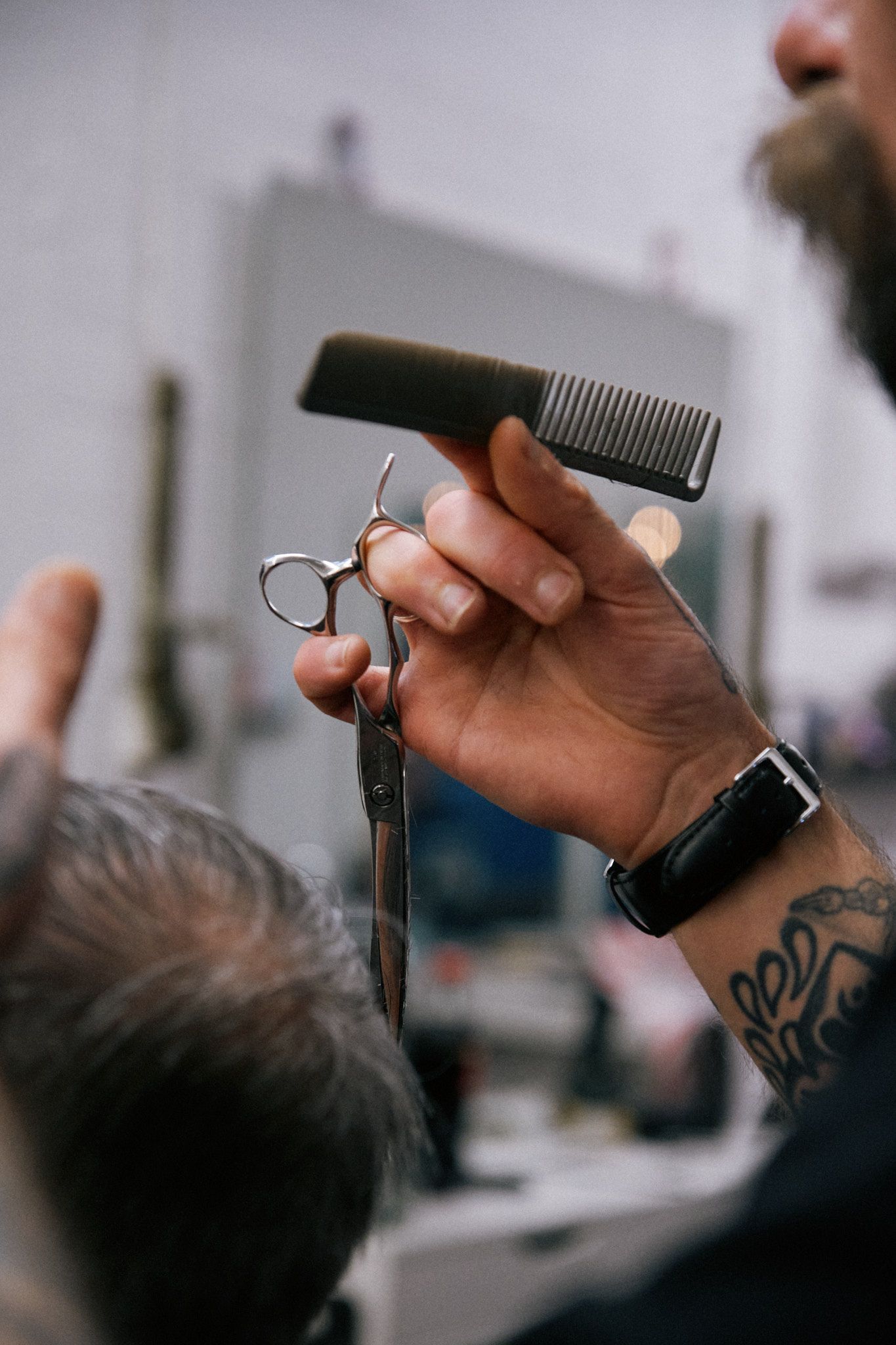 Close-up sequence of tattooed hands holding a black hair comb against a blurred background.